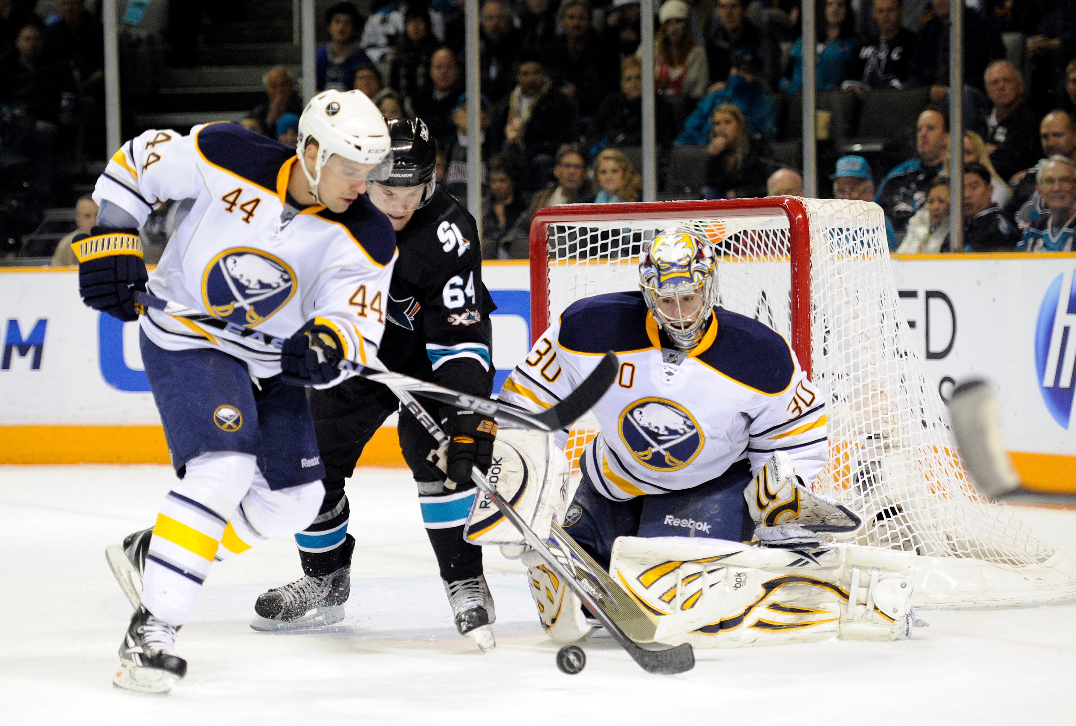 SAN JOSE, CA - JANUARY 6:  Jamie McGinn #64 of the San Jose Sharks battles for the puck with Andrej Sekera #44 of the Buffalo Sabres in front of goalie Ryan Miller #30  during an NHL hockey game at the HP Pavilion on January 6, 2011 in San Jose, Californi