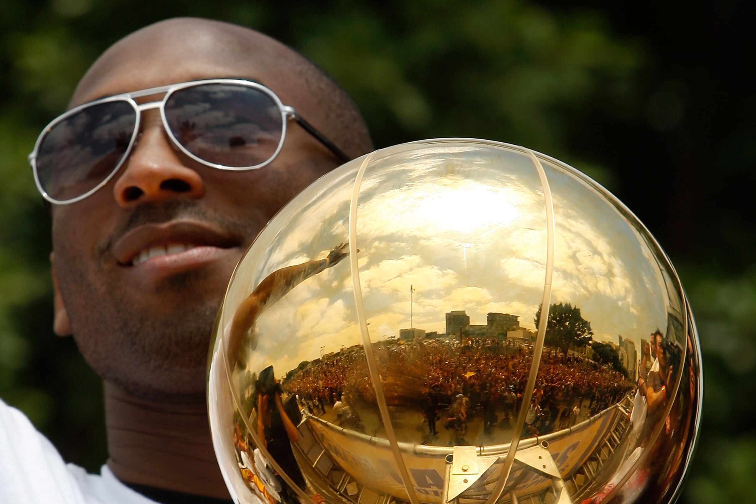 LOS ANGELES, CA - JUNE 21:  The crowd is reflected in the championship trophy held by Los Angeles Lakers guard Kobe Bryant as he rides in the victory parade for the the NBA basketball champion team on June 21, 2010 in Los Angeles, California. The Lakers b