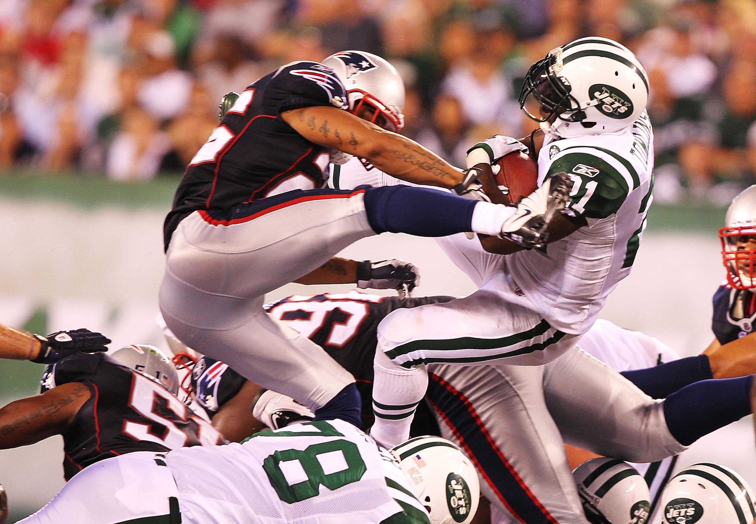 EAST RUTHERFORD, NJ - SEPTEMBER 19:  LaDainian Tomlinson #21  of the New York Jets leaps to a first down in the fourth quarter as Patrick Chung #25  of the New England Patriots delivers the hit during their  game on September 19, 2010 at the New Meadowlan