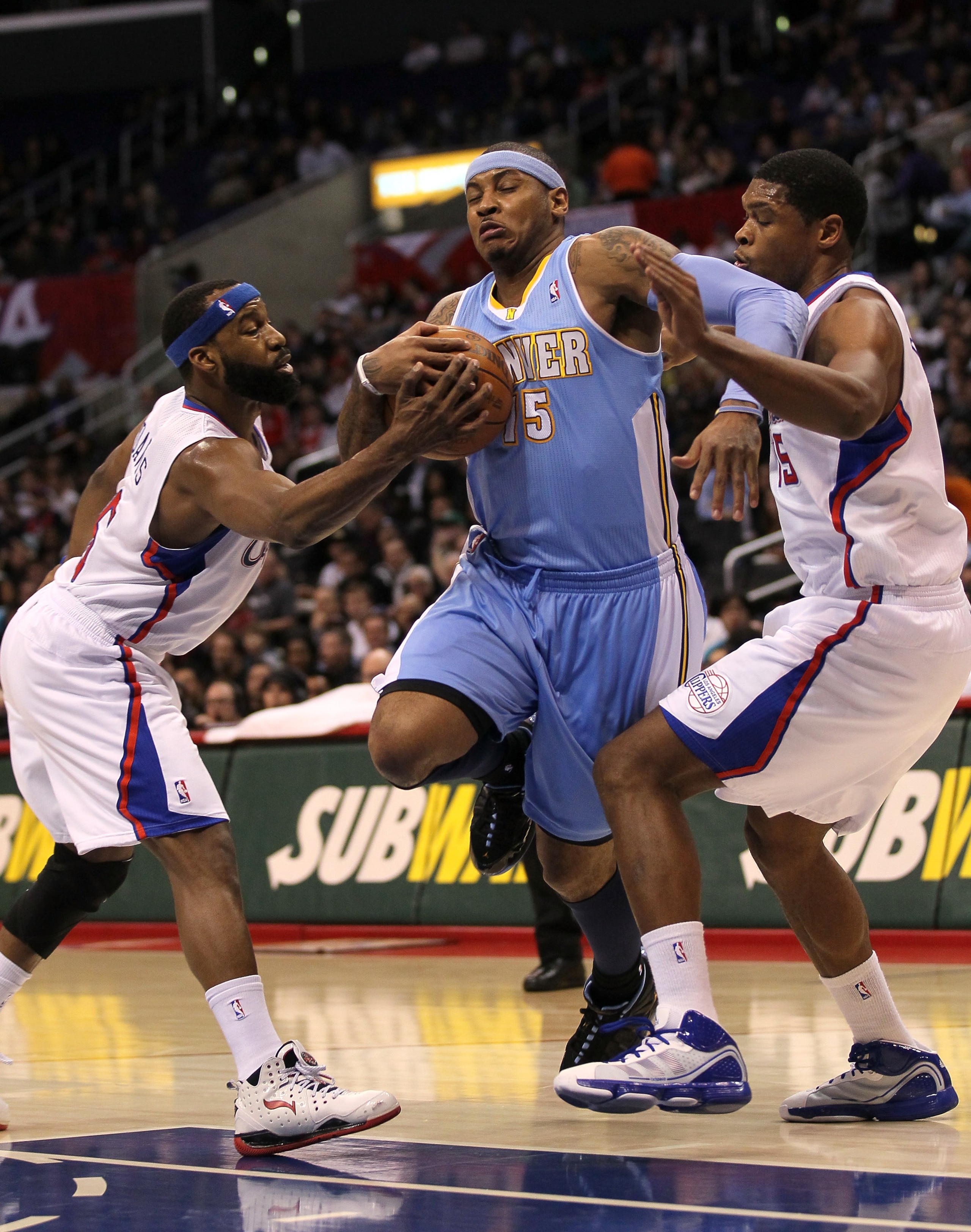 LOS ANGELES, CA - JANUARY 05:  Carmelo Anthony #15 of the Denver Nuggets fights to drive through Baron Davis #5 and Ryan Gomes #15 of the Los Angeles Clippers at Staples Center on January 5, 2011  in Los Angeles, California.  NOTE TO USER: User expressly