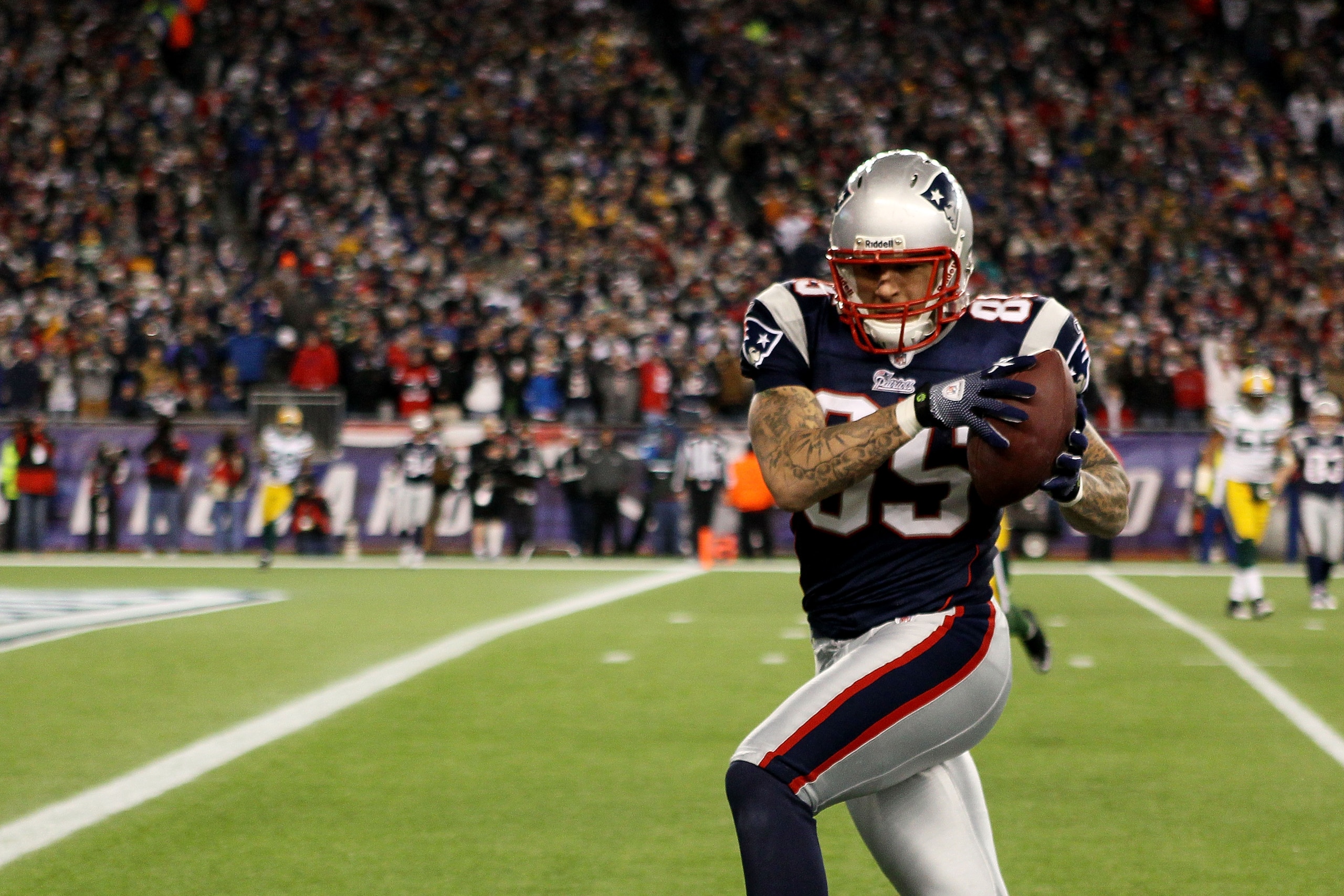 FOXBORO, MA - DECEMBER 19:  Tight end Aaron Hernandez #85 of the New England Patriots catches a pass from quarterback Tom Brady #12 (not pictured) to run it in for a touchdown in the fourth quarter against the Green Bay Packers at Gillette Stadium on Dece