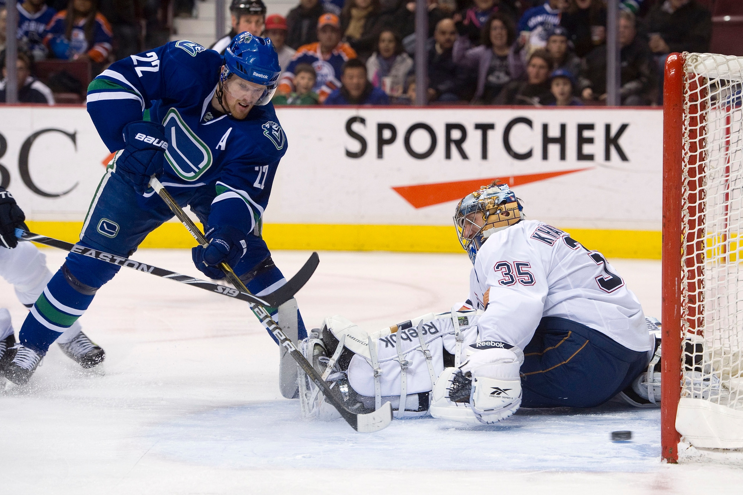 VANCOUVER, CANADA - JANUARY 7: Daniel Sedin #22 of the Vancouver Canucks slides a backhand shot past goalie Nikolai Khabibulin #35 of the Edmonton Oilers for his second goal of the night during the second period at Rogers Arena January 7, 2011 in Vancouve