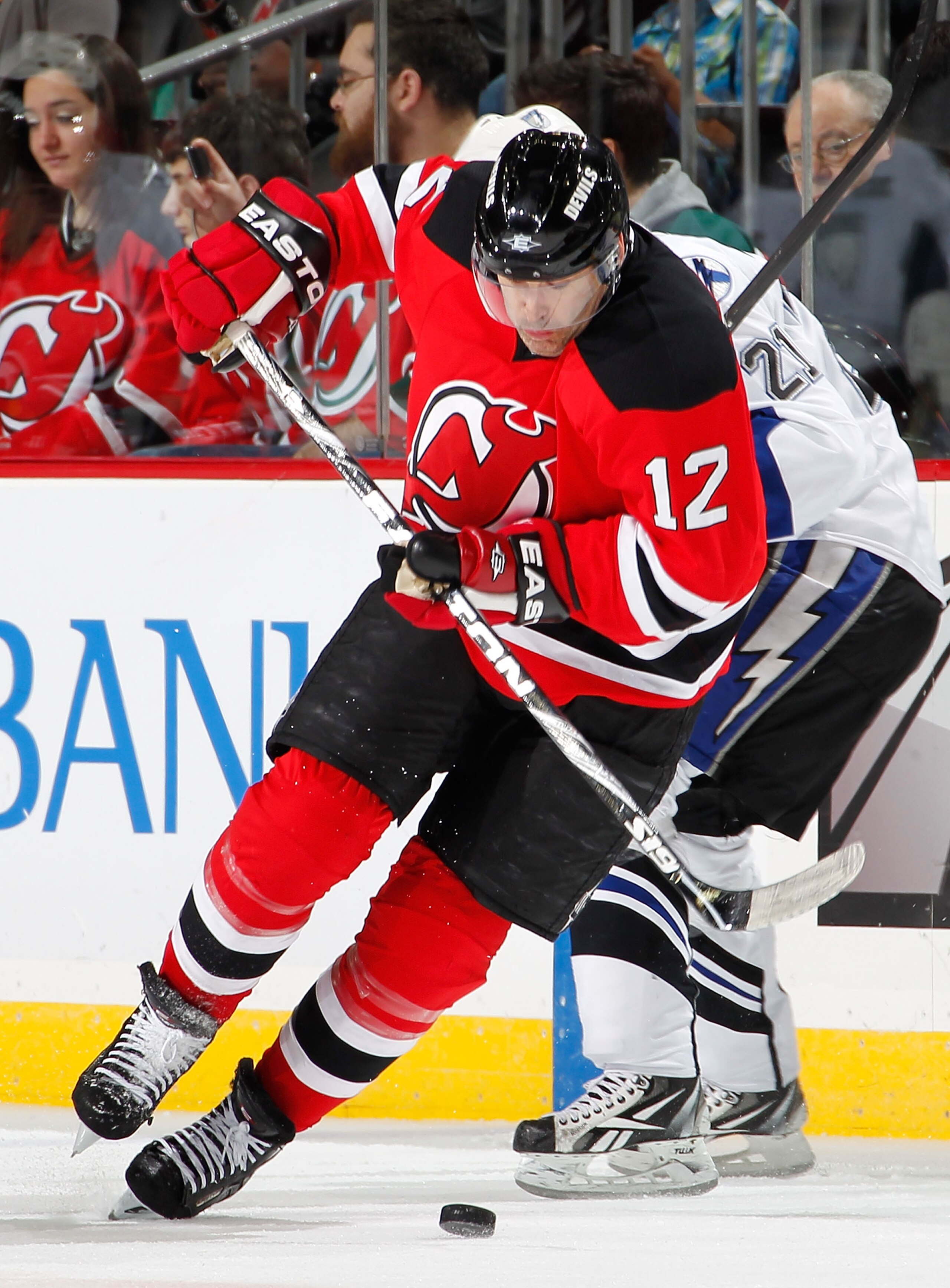 NEWARK, NJ - JANUARY 09:  Brian Rolston #12 of the New Jersey Devils skates past Mattias Ritola #21 of the Tampa Bay Lightning in the first period of an NHL hockey game at the Prudential Center on January 9, 2011 in Newark, New Jersey.  (Photo by Paul Ber