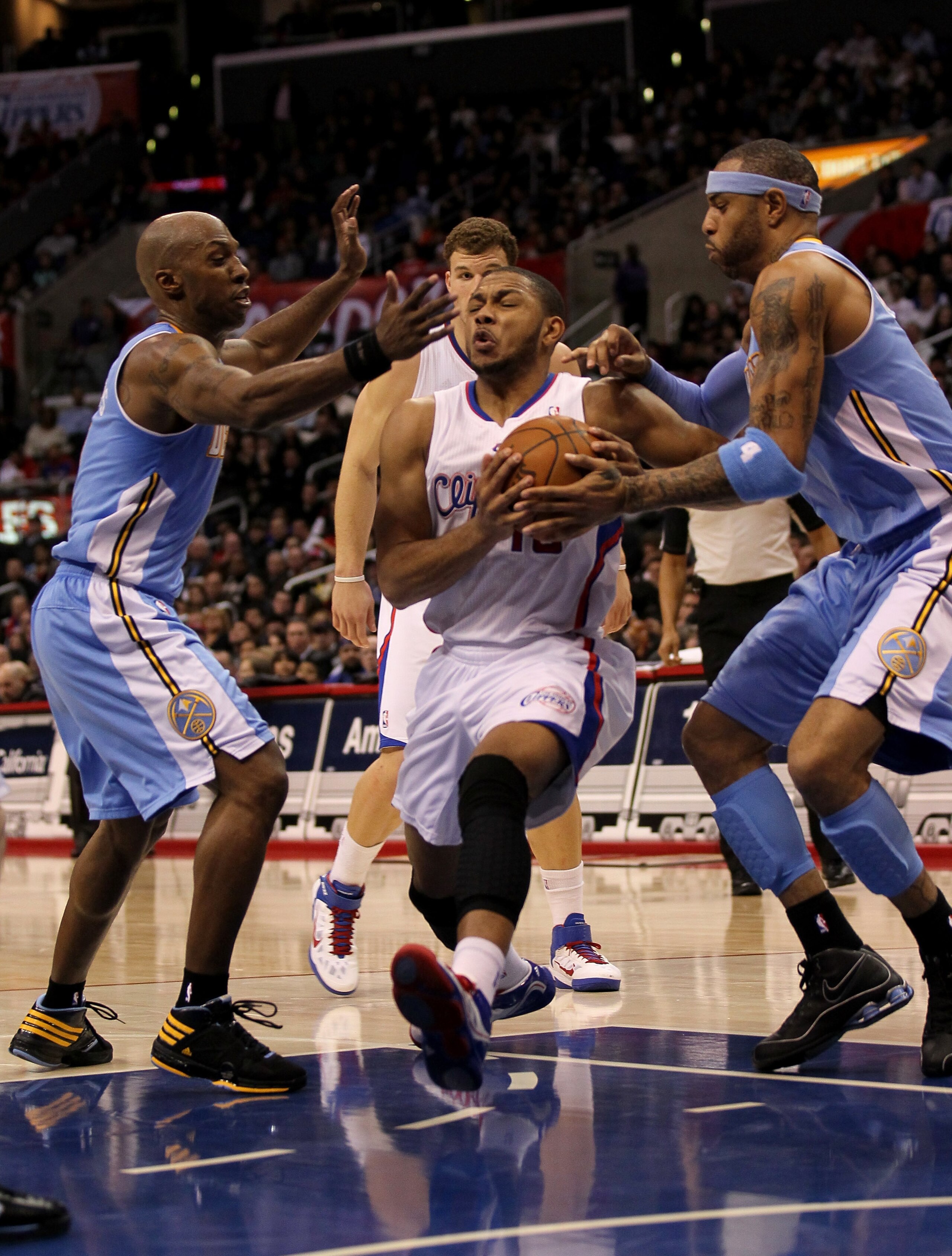 LOS ANGELES, CA - JANUARY 05:  Eric Gordon #10 of the Los Angeles Clippers drives between Kenyon Martin #4 and Chauncey Billups #1 of the Denver Nuggets at Staples Center on January 5, 2011  in Los Angeles, California. Nene was charged with a foul on the 