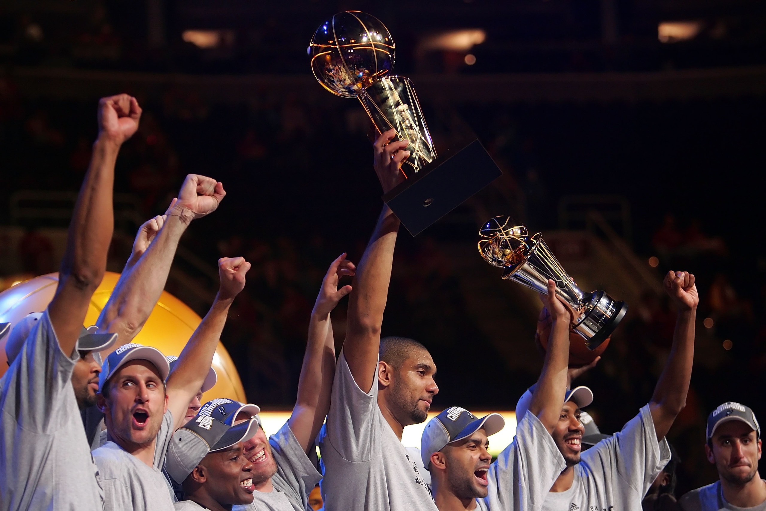 CLEVELAND - JUNE 14:  Members of the San Antonio Spurs celebrate the win as Tim Duncan #21 holds up the Larry O'Brien Championship Trophy and Tony Parker #9 holds up the MVP trophy after winning Game Four of the NBA Finals against the Cleveland Cavaliers