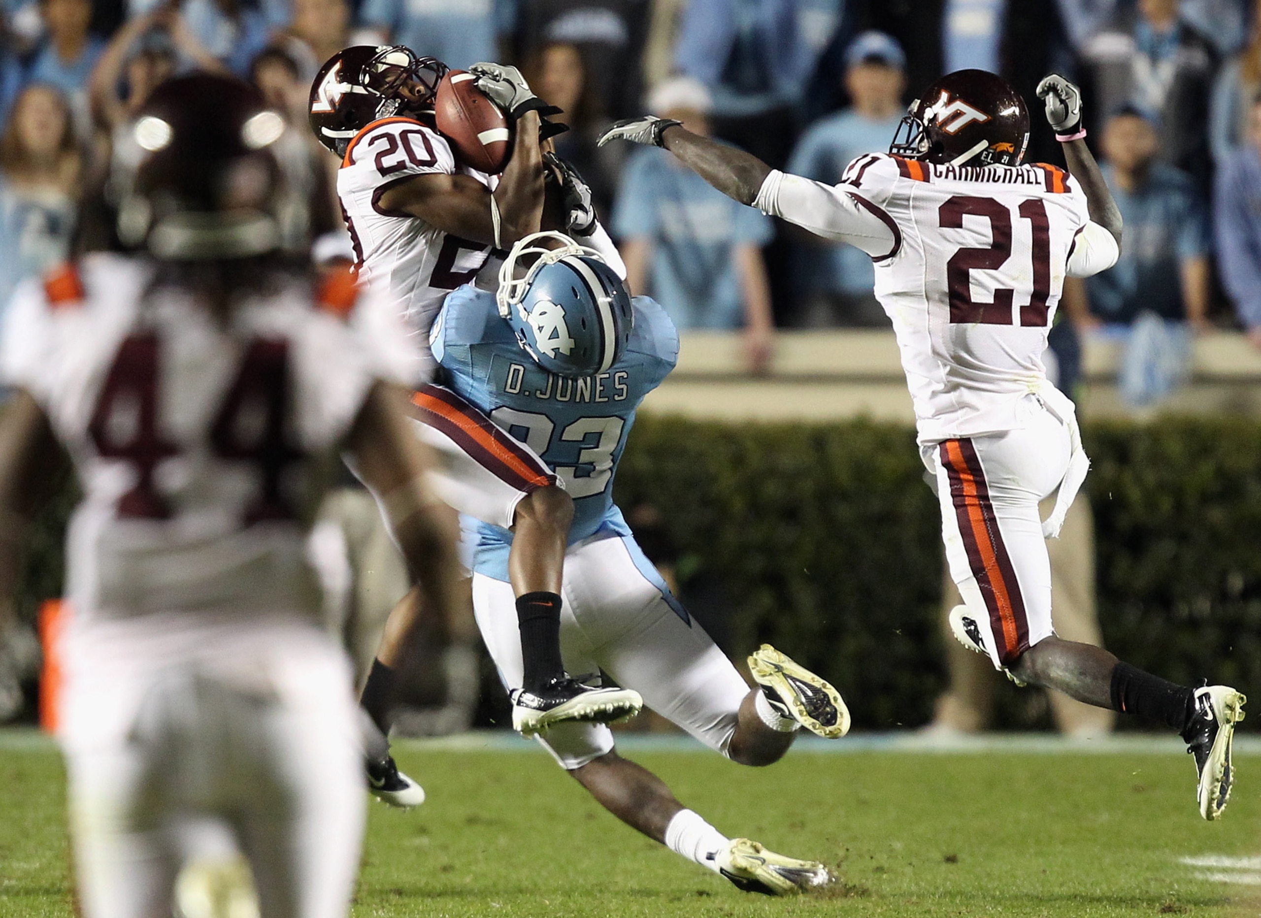 CHAPEL HILL, NC - NOVEMBER 13:  Jayron Hosley #20 of the Virginia Tech Hokies makes an interception as teammate Rashad Carmichael #21 watches on with Dwight Jones #83 of the North Carolina Tar Heels during their game at Kenan Stadium on November 13, 2010
