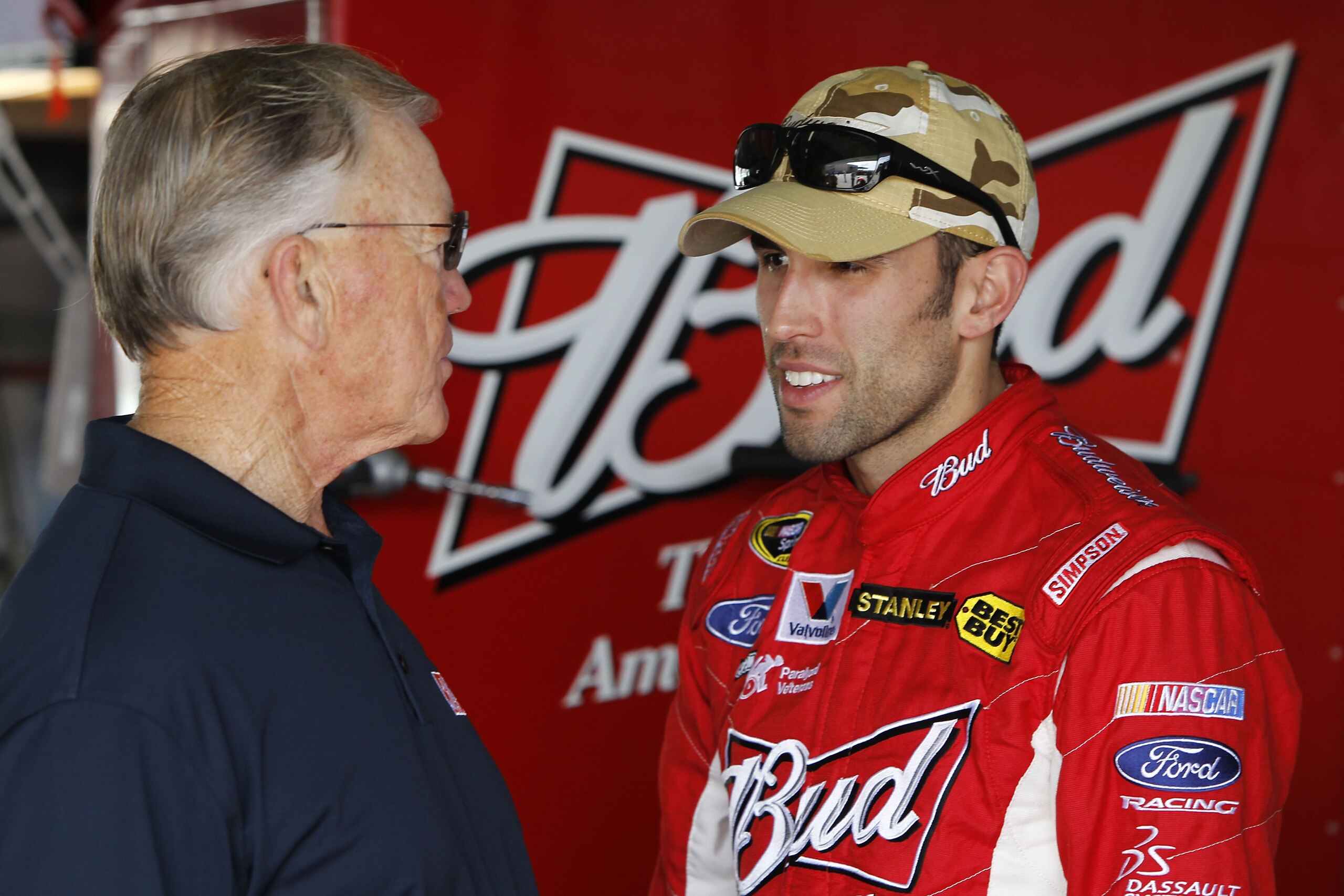 HOMESTEAD, FL - NOVEMBER 20:  Team owner Joe Gibbs (L) talks with Aric Almirola, driver of the #9 Budweiser Ford, in the garage during practice for the NASCAR Sprint Cup Series Ford 400 at Homestead-Miami Speedway on November 20, 2010 in Homestead, Florid