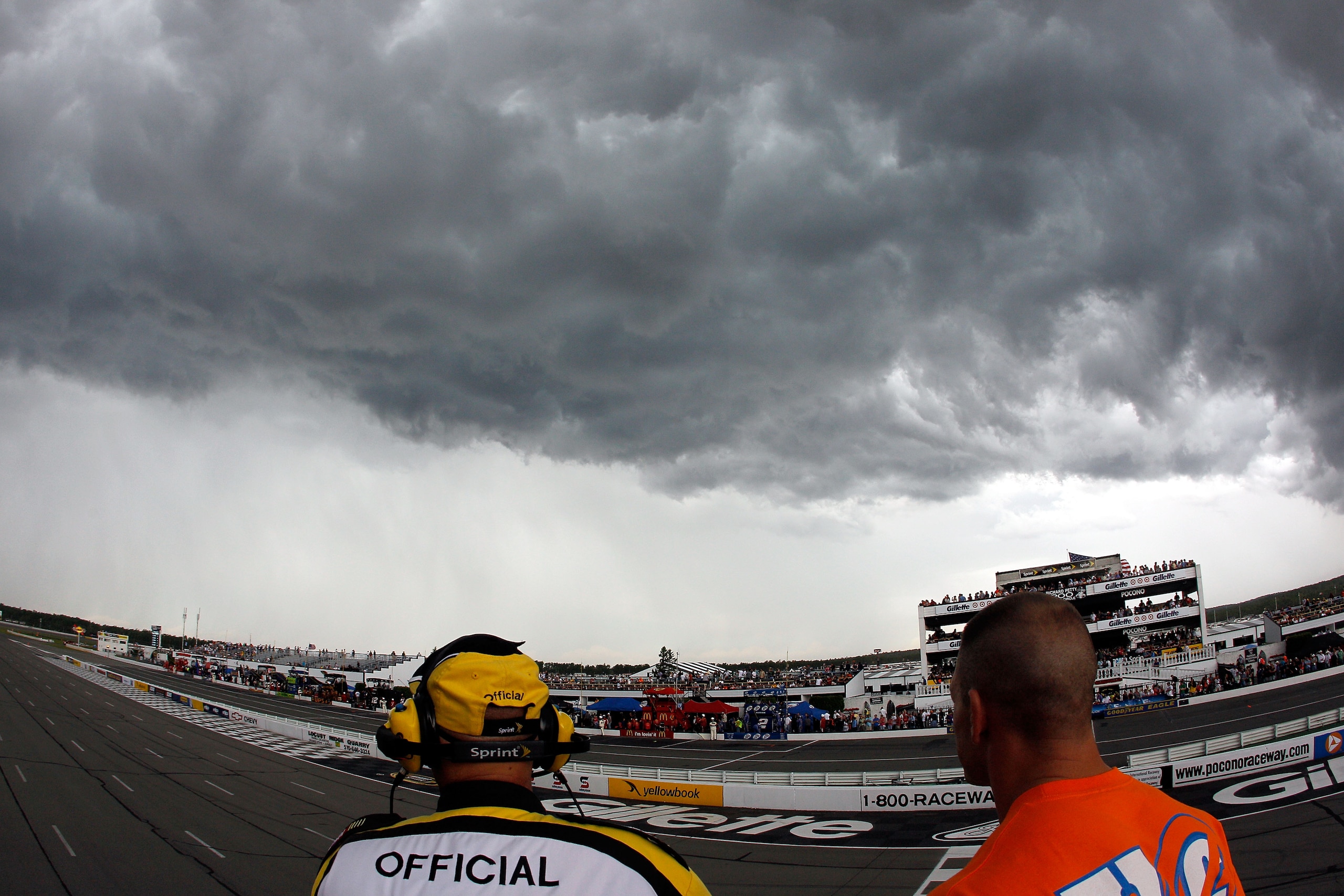LONG POND, PA - JUNE 06:  WWE champion/co-grand marshal John Cena (R) and NASCAR official Rick Monroe (L) watch the weather as rain falls to delay the NASCAR Sprint Cup Series Gillette Fusion ProGlide 500 at Pocono Raceway on June 6, 2010 in Long Pond, Pe