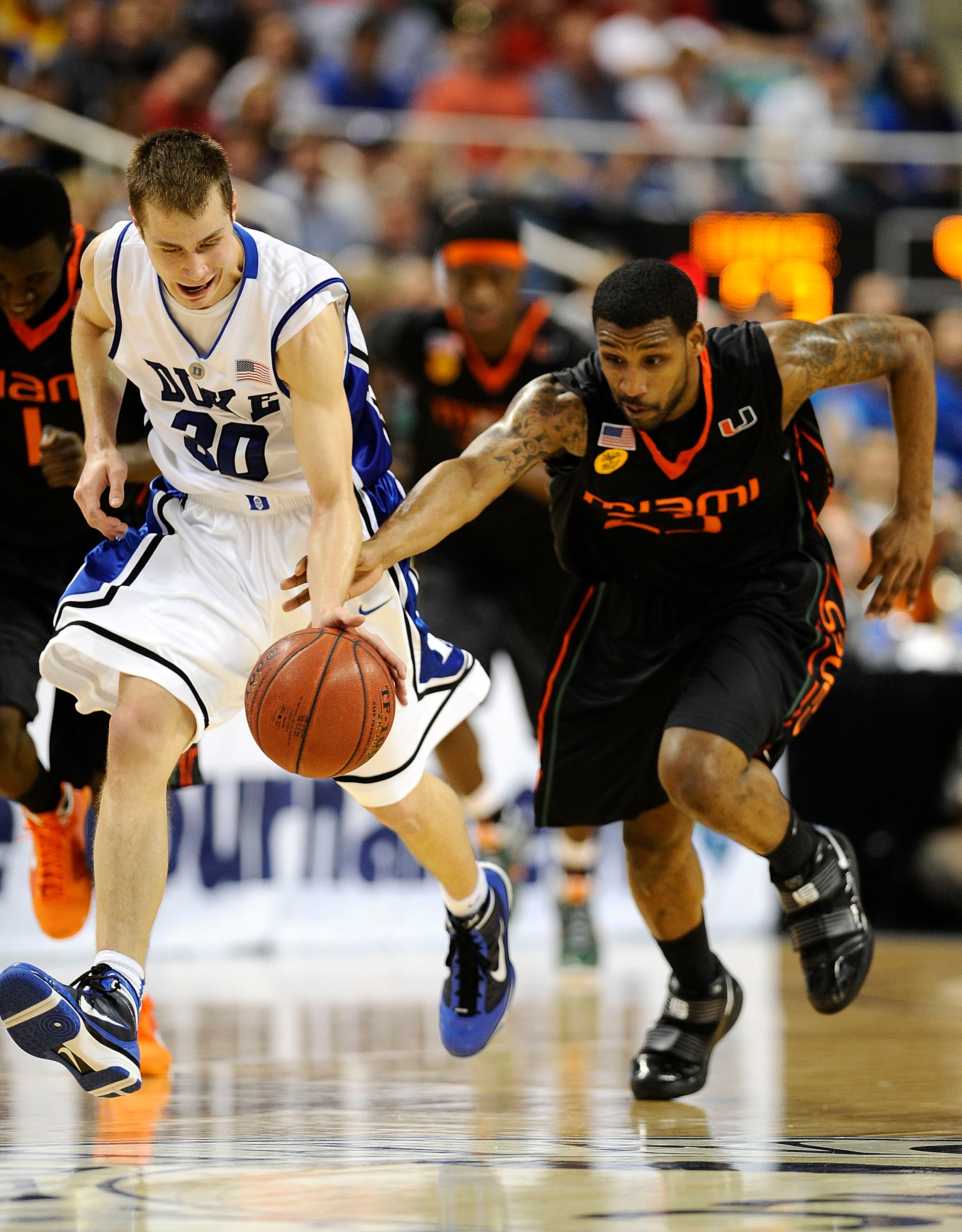 GREENSBORO, NC - MARCH 13:  Jon Scheyer #30 of the Duke Blue Devils and James Dews #23 of the University of Miami Hurricanes chase a ball in their semifinal game in the 2010 ACC Men's Basketball Tournament at the Greensboro Coliseum on on March 13, 2010 i