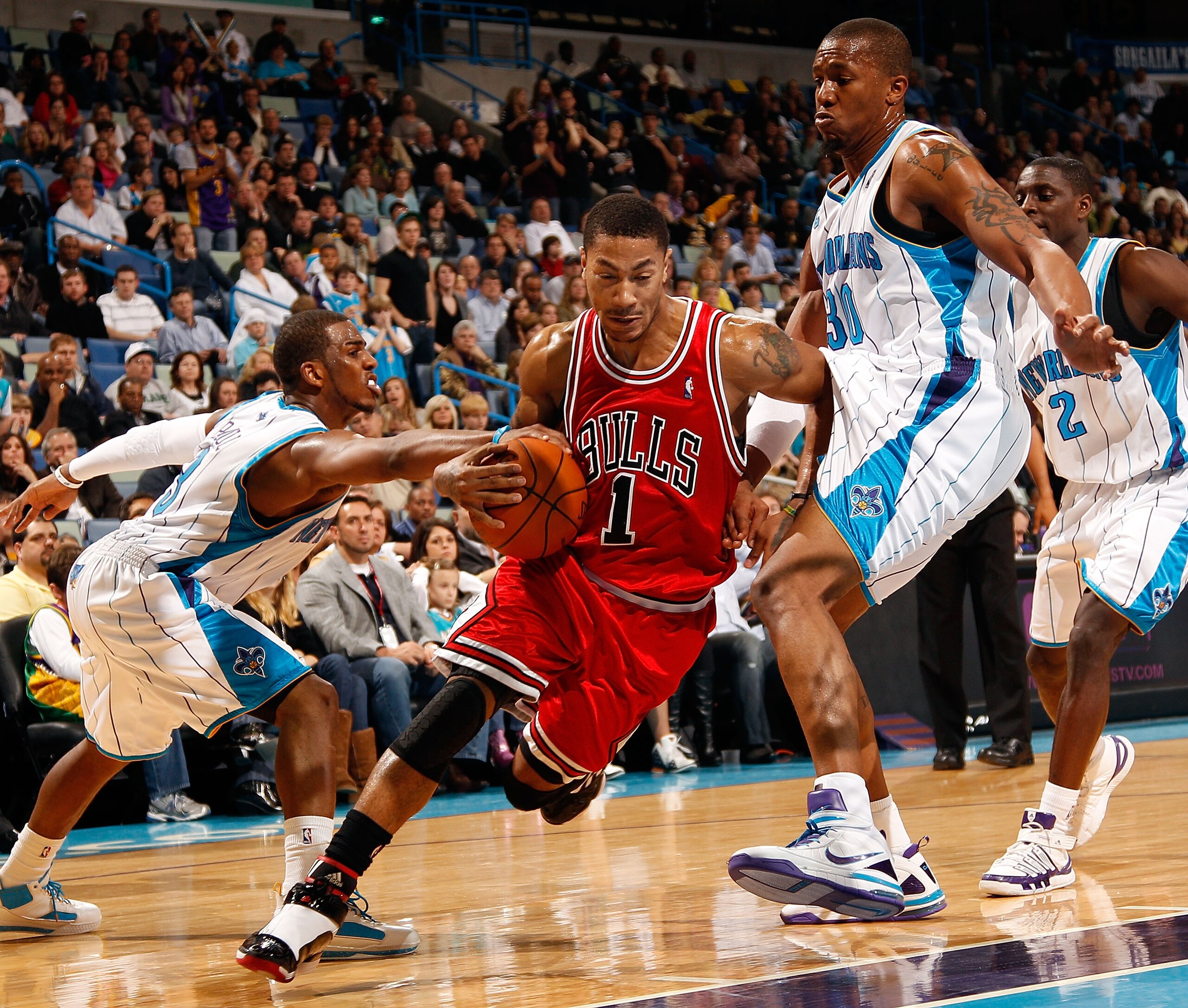 NEW ORLEANS - JANUARY 29:  Derrick Rose #1 of the Chicago Bulls drives the ball around Chris Paul #3 and David West #30 of the New Orleans Hornets at the New Orleans Arena on January 29, 2010 in New Orleans, Louisiana.   The Bulls defeated the Hornets 108