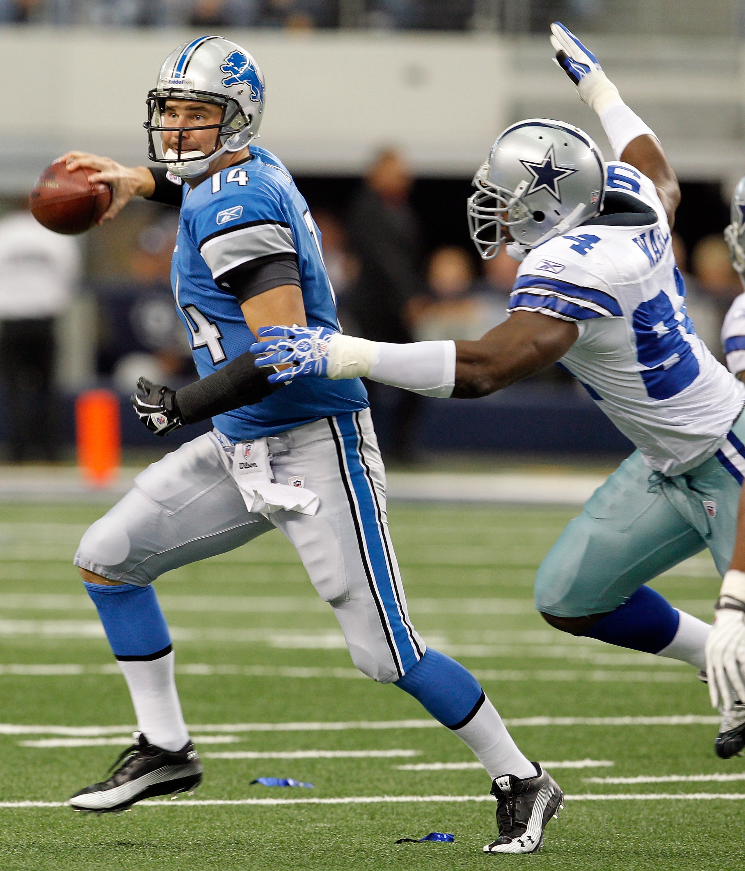 ARLINGTON, TX - NOVEMBER 21:  Quarterback Shaun Hill #14 of the Detroit Lions scrambles with the ball under pressure by Demarcus Ware #94 of the Dallas Cowboys at Cowboys Stadium on November 21, 2010 in Arlington, Texas.  The Cowboys beat the Lions 35-19.