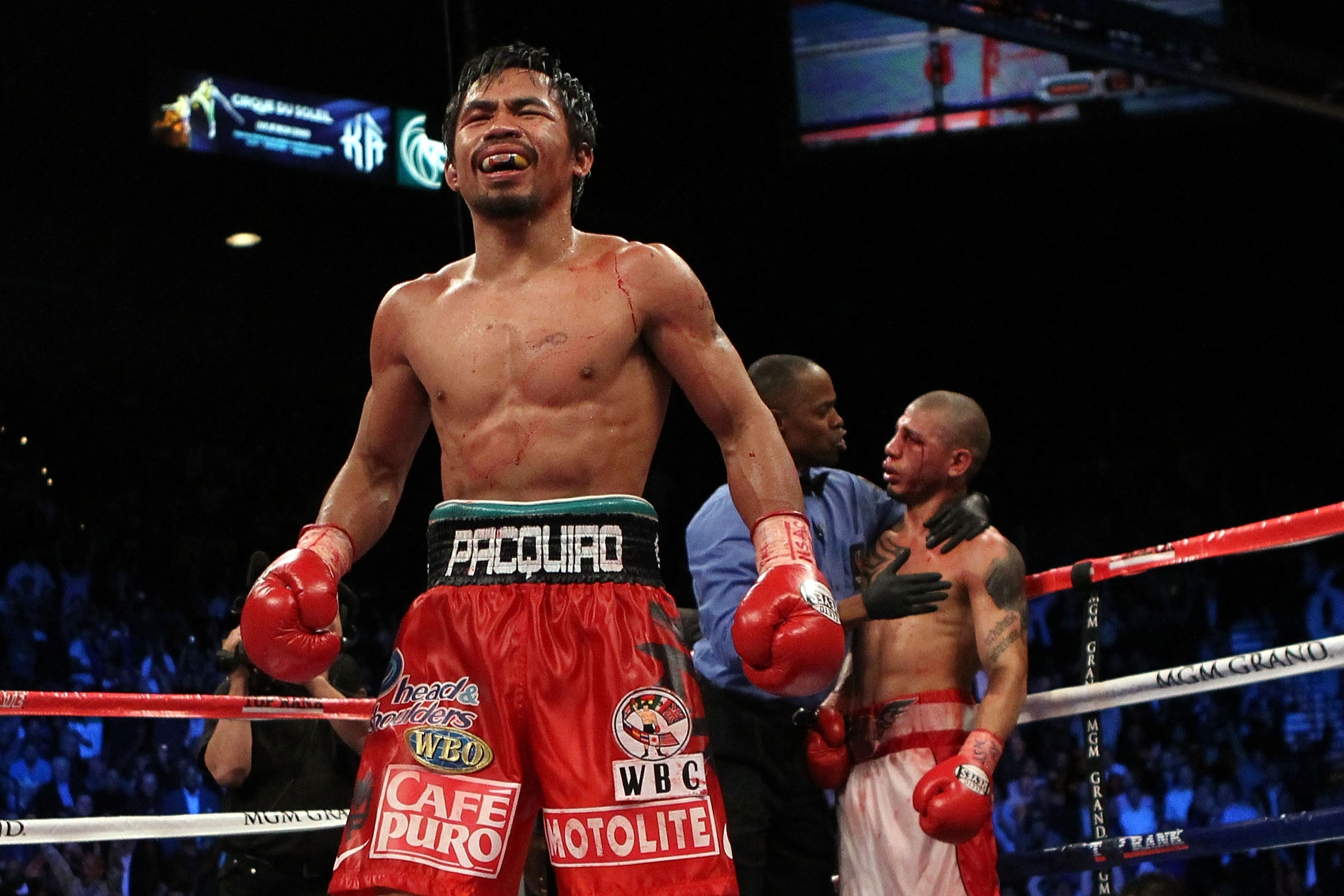 LAS VEGAS - NOVEMBER 14:  Manny Pacquiao celebrates his 12 round TKO victory against Miguel Cotto as Cotto is consoled by referee Kenny Bayless after their WBO welterweight title fight at the MGM Grand Garden Arena on November 14, 2009 in Las Vegas, Nevad
