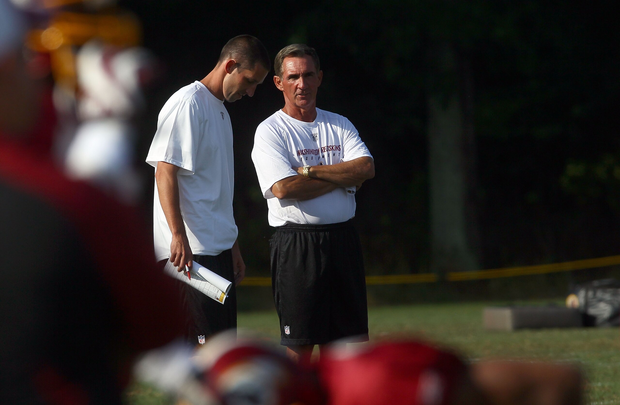 ASHBURN, VA - JULY 30:  Head coach Mike Shanahan (R) of the Washington Redskins speaks with his son and offensive coordinator, Kyle Shanahan (R), during the second day of training camp July 30, 2010 in Ashburn, Virginia.  (Photo by Win McNamee/Getty Image