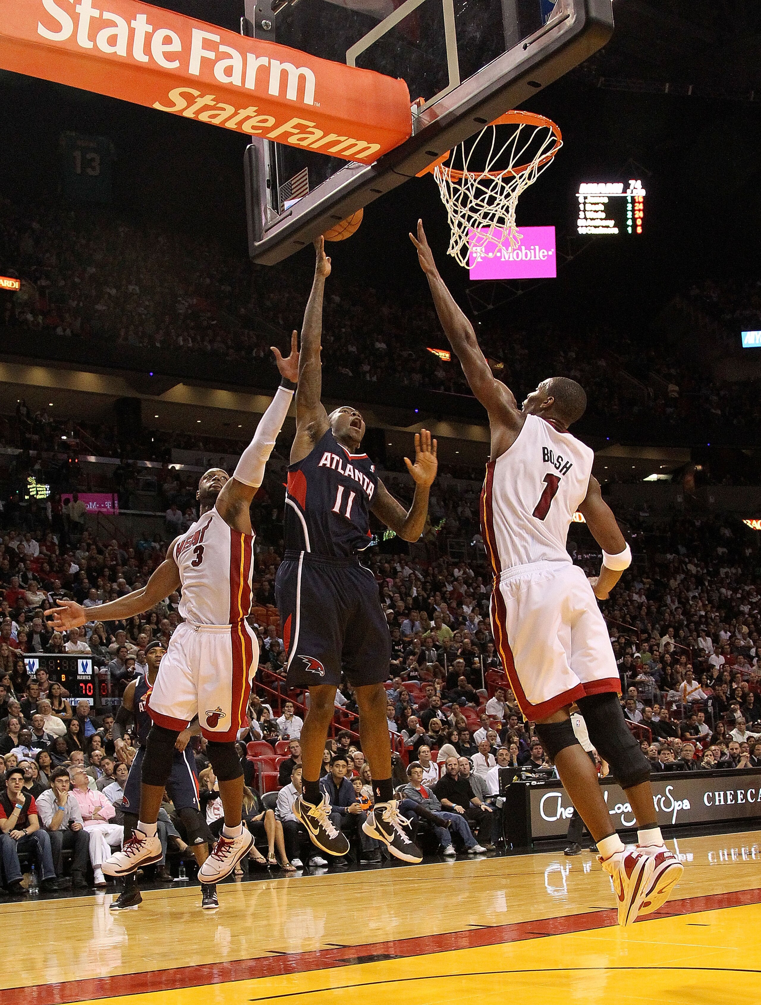 MIAMI, FL - DECEMBER 04:  Jamal Crawford #11 of the Atlanta Hawks drives to the basket against Chris Bosh #1 and Dwyane Wade #3 of the Miami Heat during a game at American Airlines Arena on December 4, 2010 in Miami, Florida. NOTE TO USER: User expressly