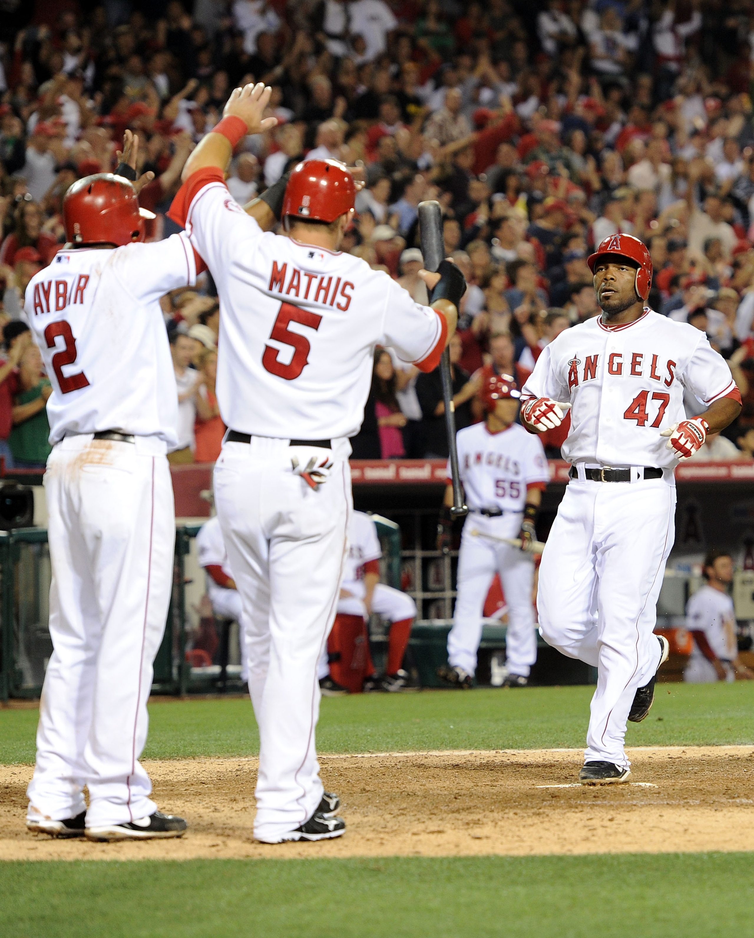 ANAHEIM, CA - JUNE 29:  Howie Kendrick #47, Erick Aybar #2 and Jeff Mathis #5 of the Los Angeles Angels celebrate a three run double by Bobby Abreu #53 to take a 6-3 lead over the Texas Rangers during the sixth inning at Angel Stadium on June 29, 2010 in