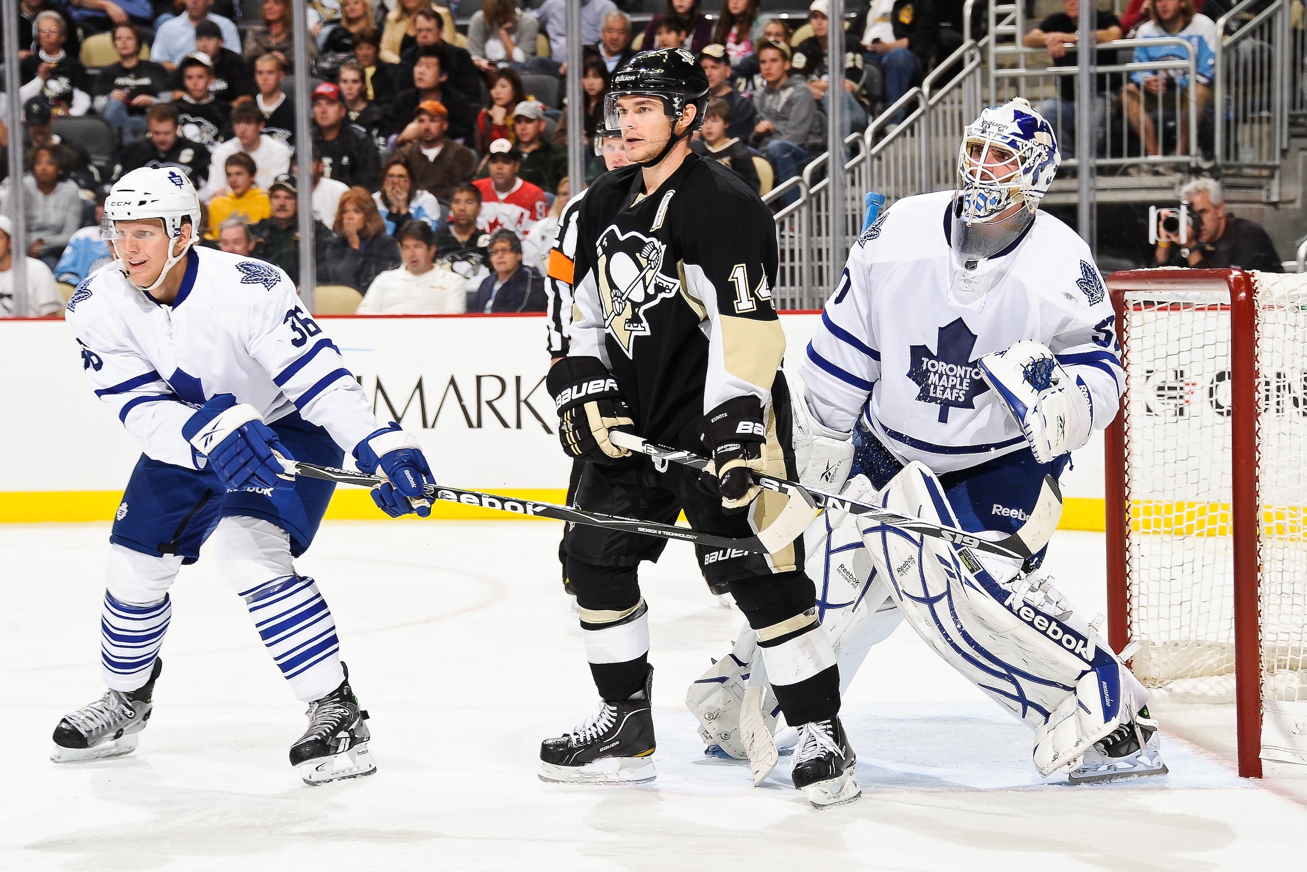 PITTSBURGH - OCTOBER 13:  Carl Gunnarsson #36 of the Toronto Maple Leafs and Chris Kunitz #14 of the Pittsburgh Penguins set up in front of goaltender Jonas Gustavsson #50 of the Toronto Maple Leafs during a Pittsburgh power play on October 13, 2010 at Co