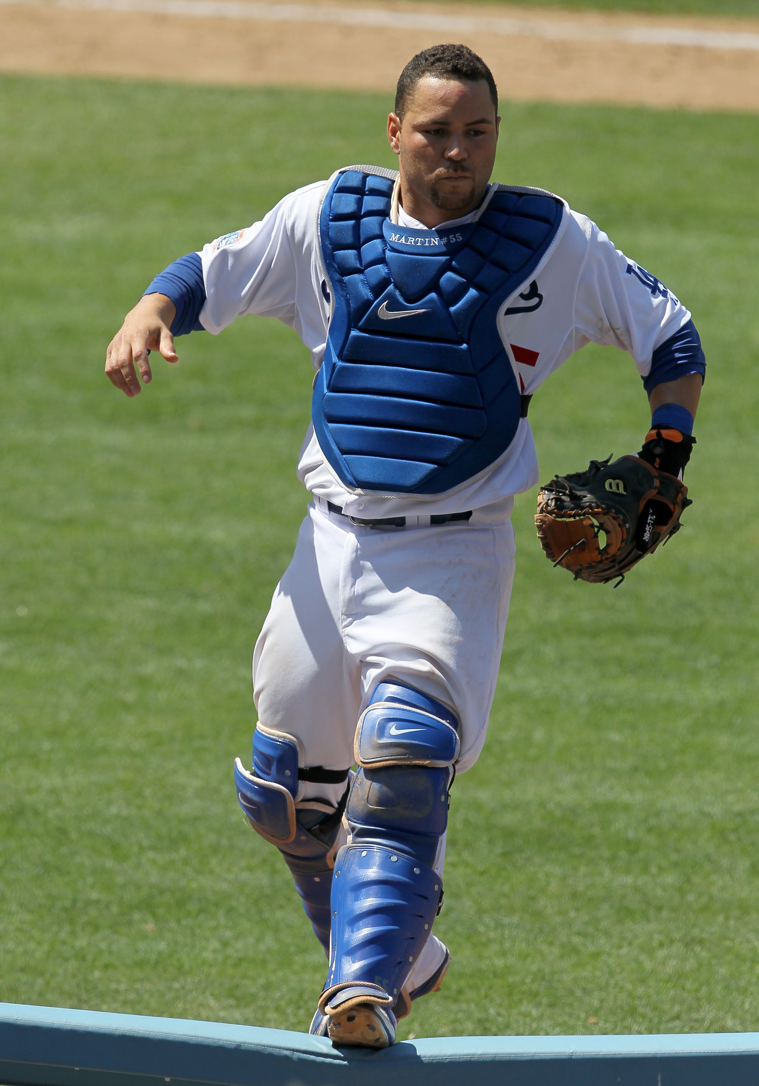 LOS ANGELES, CA - JULY 25:  Catcher Russell Martin #55 of the Los Angeles Dodgers jumps onto a rail beside the New York Mets dugouts as he pursues a pop foul ball that fell into the stands on July 25, 2010 at Dodger Stadium in Los Angeles, California.   T