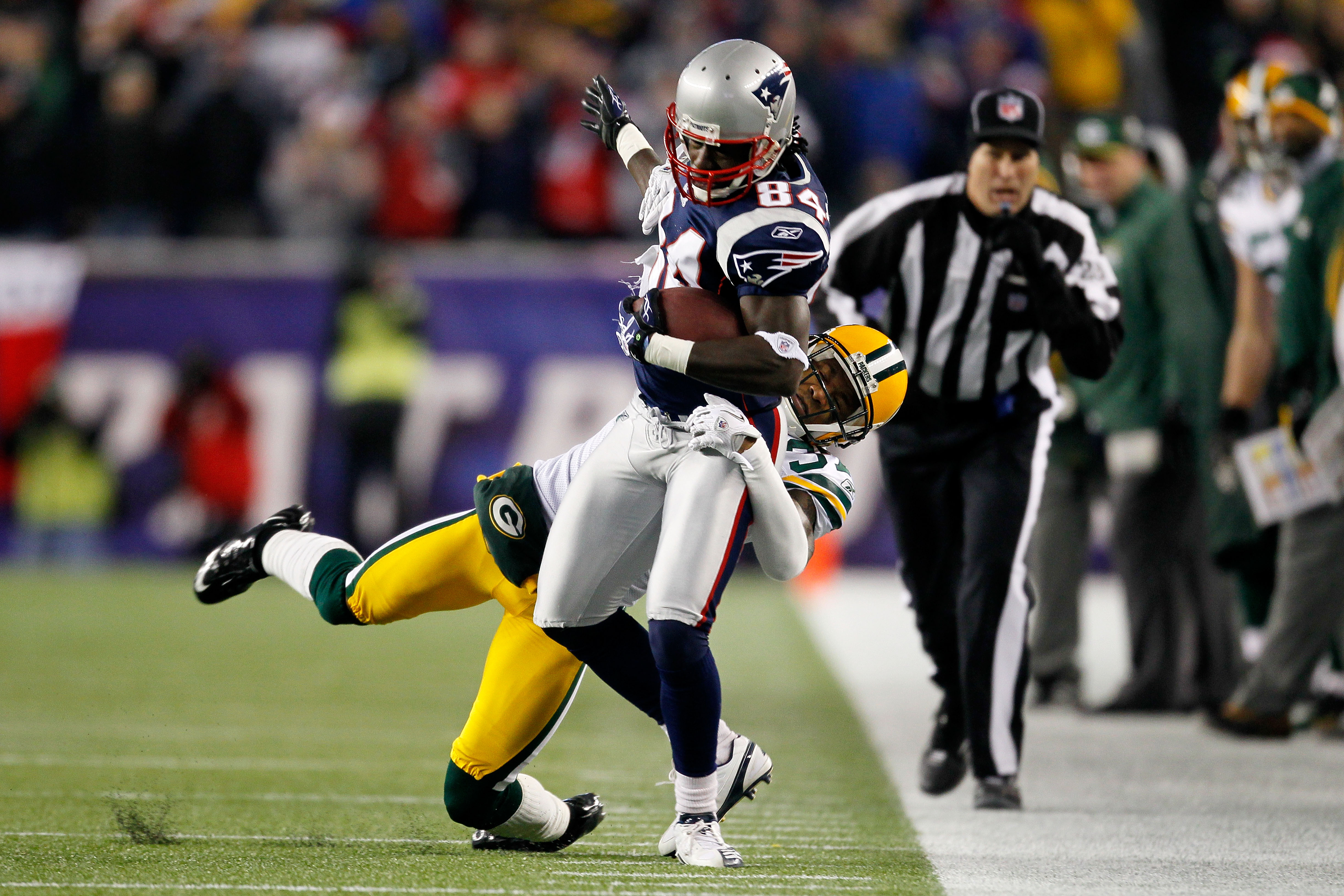 FOXBORO, MA - DECEMBER 19:  Wide receiver Deion Branch #84 of the New England Patriots is tackled by cornerback Sam Shields #37 of the Green Bay Packers during the first quarter at Gillette Stadium on December 19, 2010 in Foxboro, Massachusetts.  (Photo b