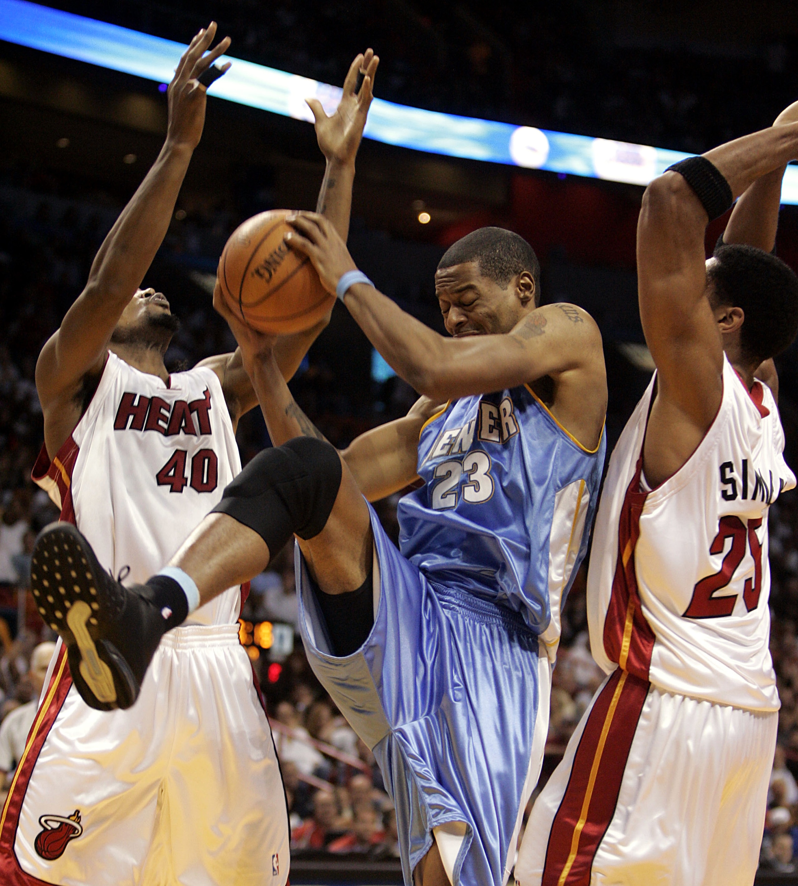 MIAMI - DECEMBER 9:  Center Marcus Camby #23 of the Denver Nuggets grabs the ball between forward Udonis Haslem #40 and forward Wayne Simien #25 of the Miami Heat on December 9, 2005 at the American Airlines Arena in Miami, Florida. NOTE TO USER: User exp