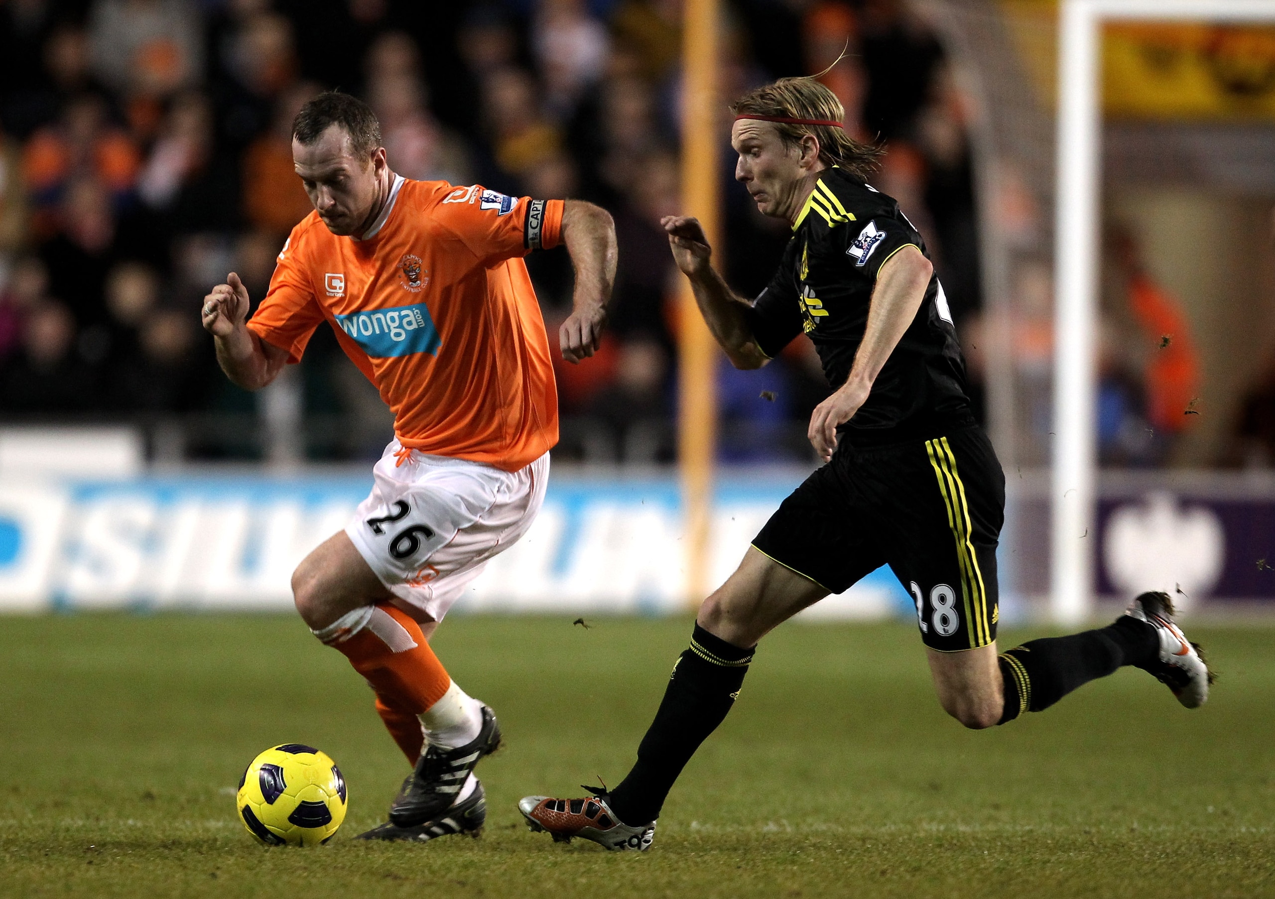 BLACKPOOL, ENGLAND - JANUARY 12:  Charlie Adam of Blackpool is pursued by Christian Poulsen of Liverpool during the Barclays Premier League match between Blackpool and Liverpool at Bloomfield Road on January 12, 2011 in Blackpool, England.  (Photo by Alex