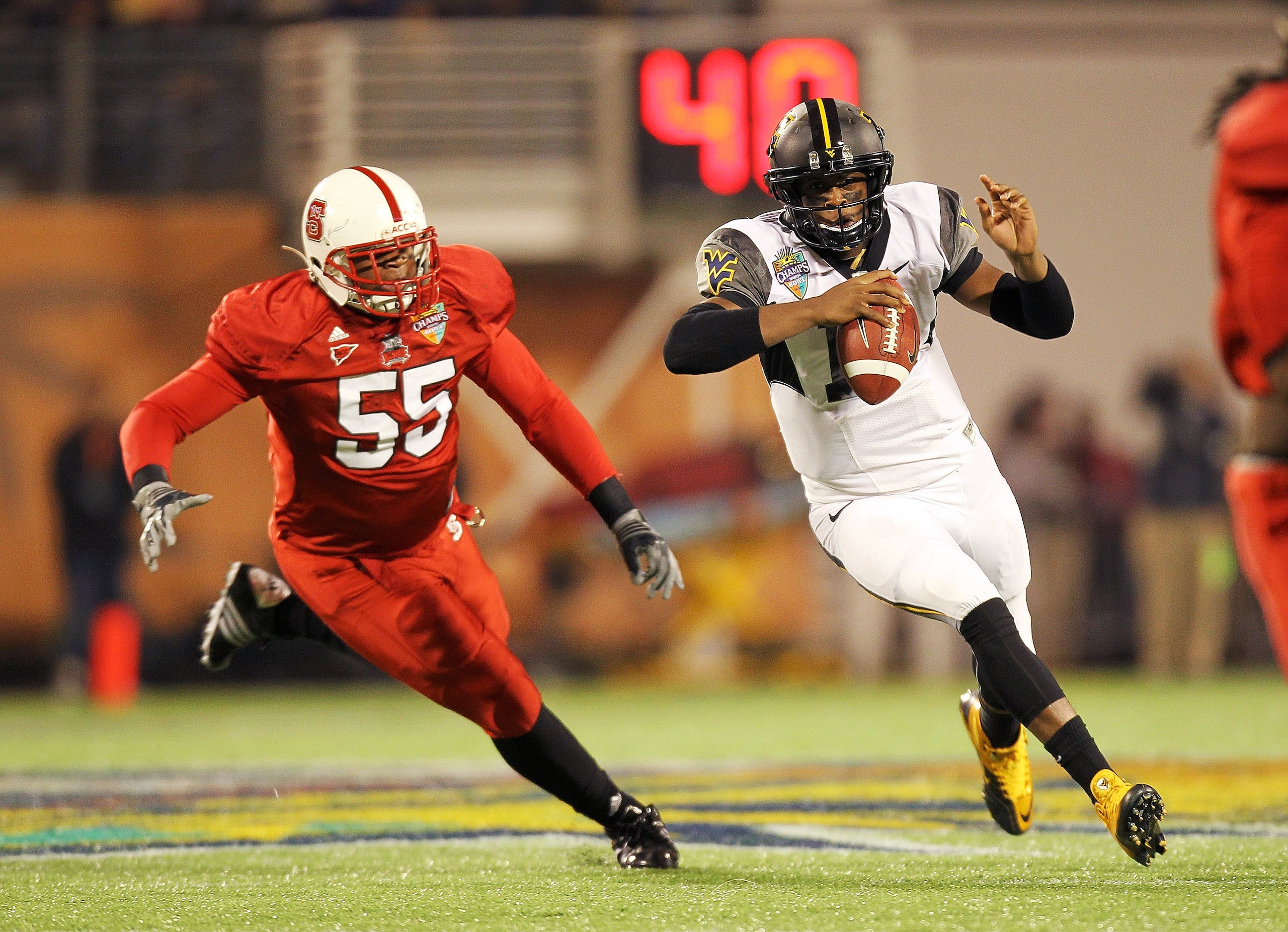 ORLANDO, FL - DECEMBER 28:  Geno Smith #12 of the West Virginia Mountineers scrambles after being chased by Brian Slay #55 of the North Carolina State Wolfpack during the Champs Sports Bowl at Florida Citrus Bowl Stadium on December 28, 2010 in Orlando, F