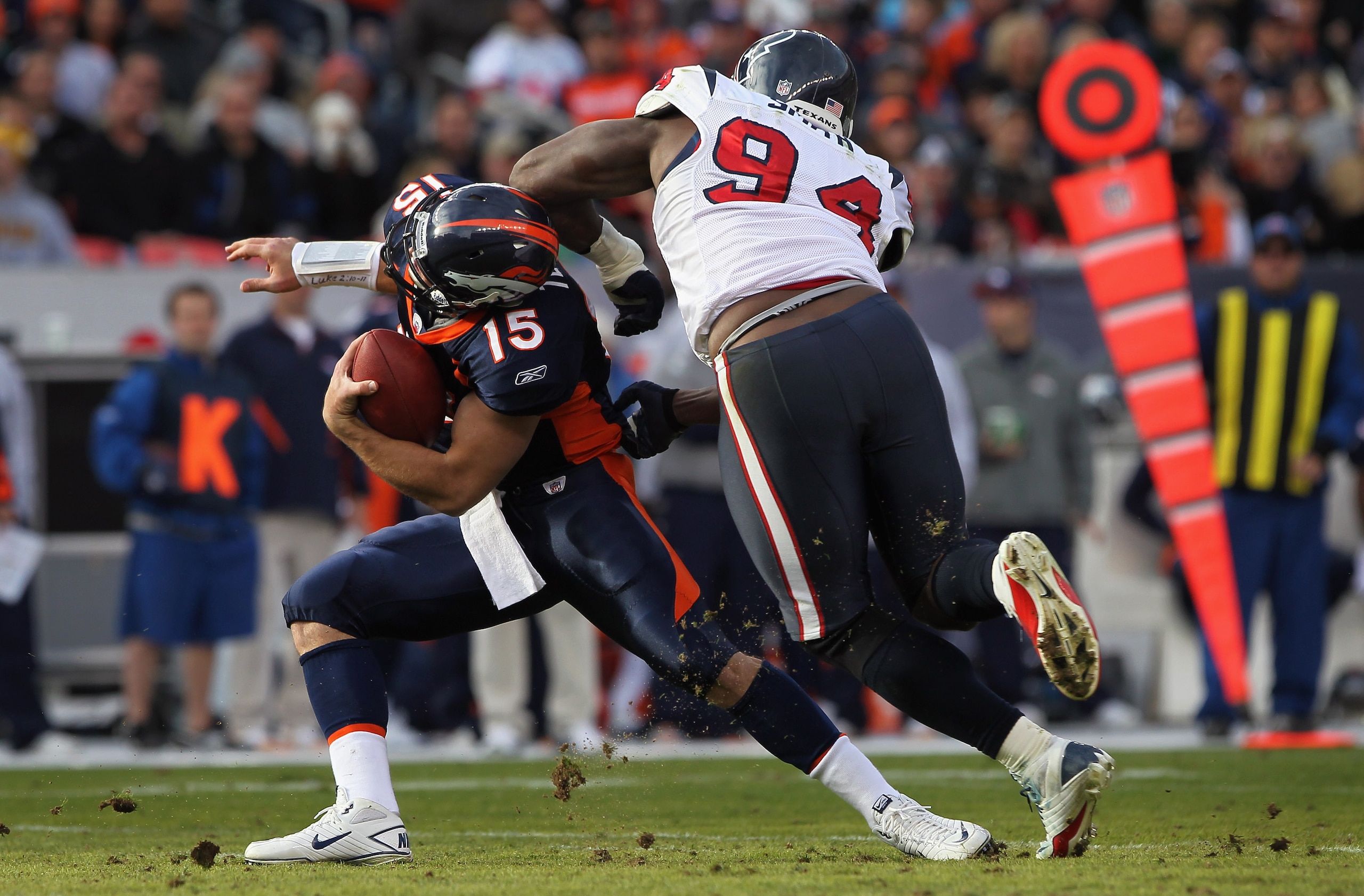 DENVER - DECEMBER 26:  Quarterback Tim Tebow #15 of the Denver Broncos eludes a sack attempt by defensive end Antonio Smith #94 of the Houston Texas at INVESCO Field at Mile High on December 26, 2010 in Denver, Colorado.  (Photo by Doug Pensinger/Getty Im