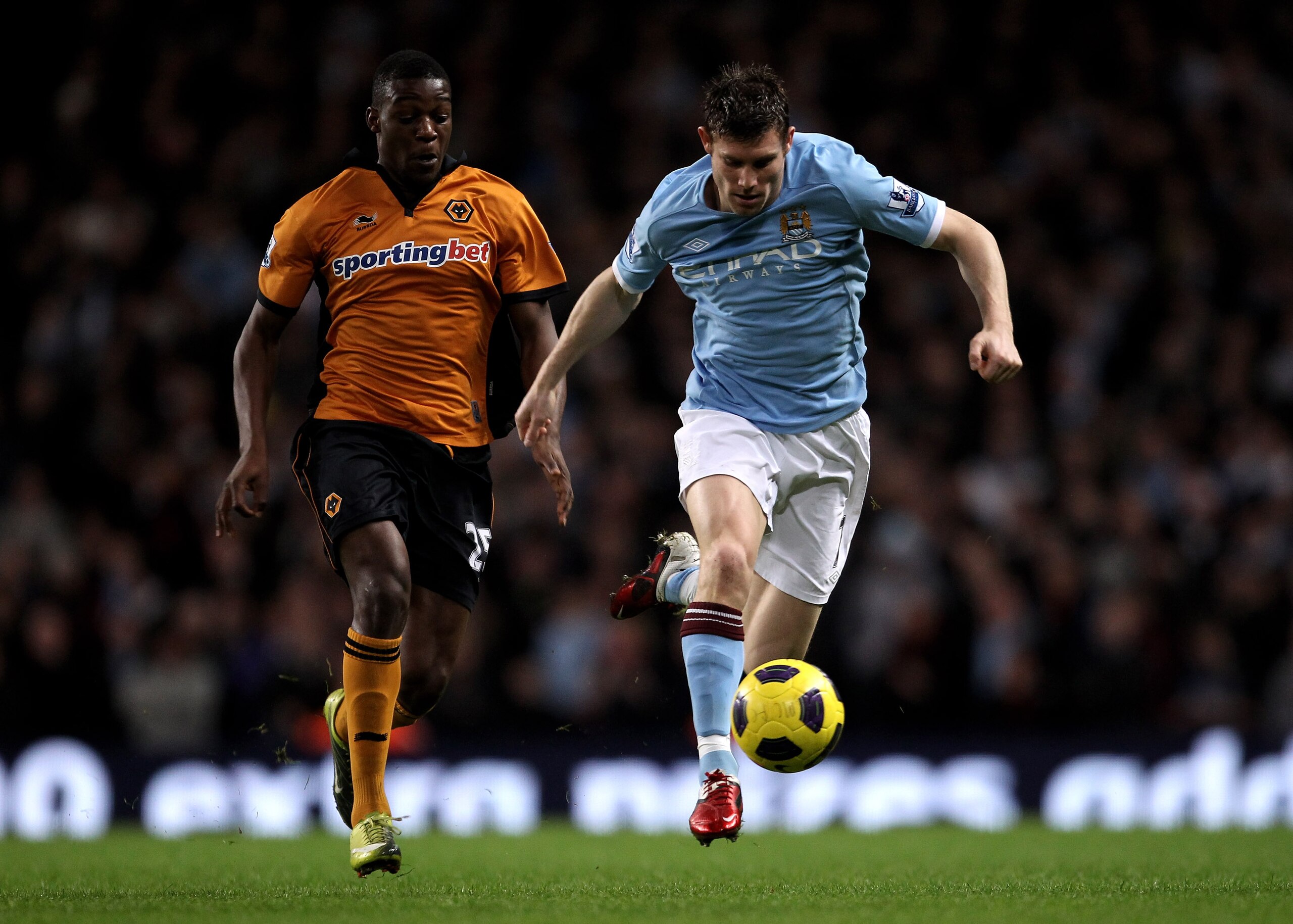 MANCHESTER, ENGLAND - JANUARY 15:  James Milner of Manchester City is pursued by Geoffrey Mujangi Bia of Wolverhampton Wanderers during the Barclays Premier League match between Manchester City and Wolverhampton Wanderers at the City of Manchester Stadium