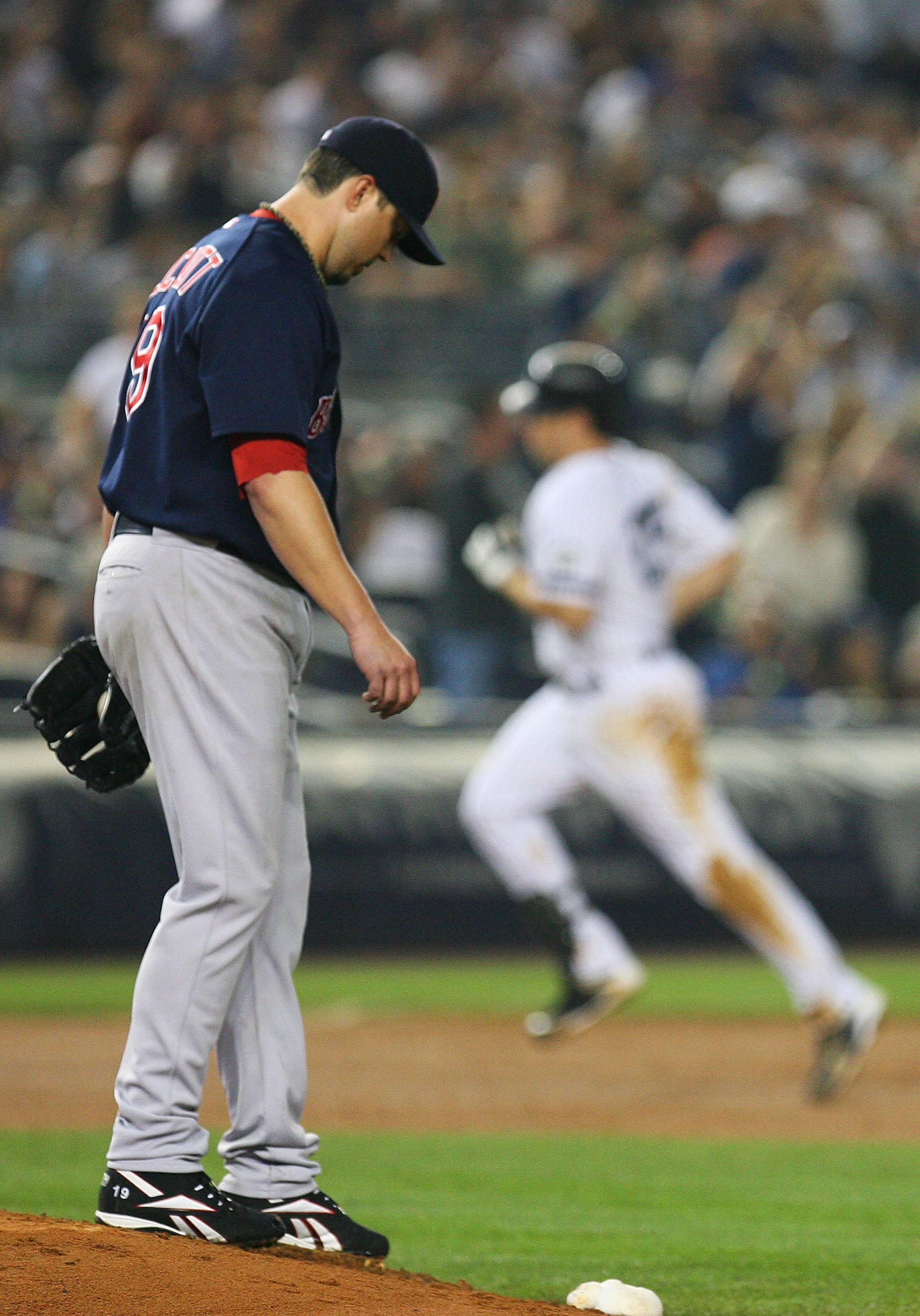 NEW YORK - SEPTEMBER 24: Josh Beckett #19 of the Boston Red Sox walks back to the mound after allowing a home run from Mark Teixeira #25 (background) of the New York Yankees in the sixth inning on September 24, 2010 at Yankee Stadium in the Bronx boroug NEW YORK - SEPTEMBER 24: Josh Beckett #19 of the Boston Red Sox walks back to the mound after allowing a home run from Mark Teixeira #25 (background) of the New York Yankees in the sixth inning on September 24, 2010 at Yankee Stadium in the Bronx boroug
