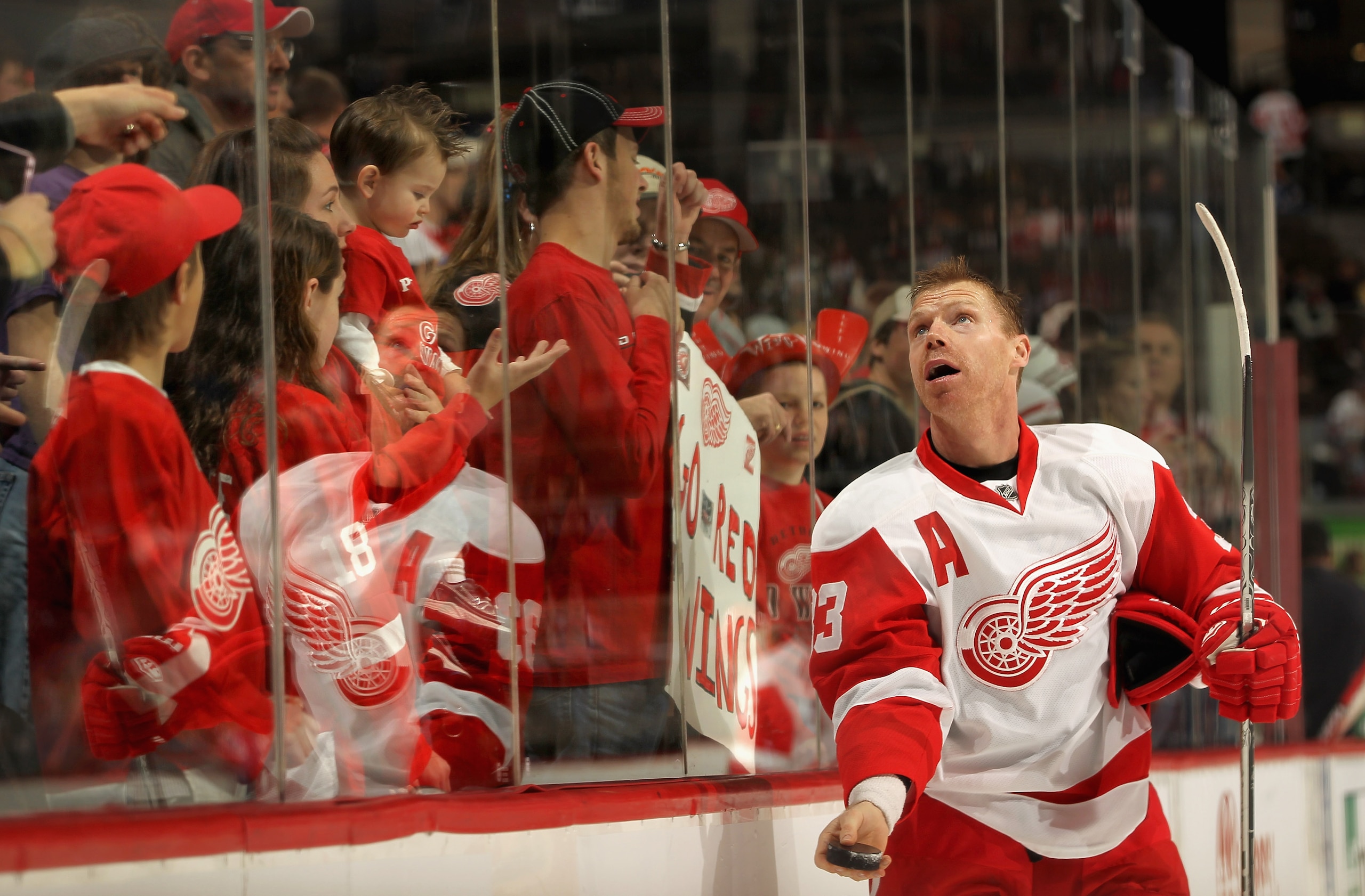 DENVER - DECEMBER 27:  Kris Draper #33 of the Detroit Red Wings tosses a puck to the fans  during warm ups as they prepare to face the Colorado Avalanche at the Pepsi Center on December 27, 2010 in Denver, Colorado.  (Photo by Doug Pensinger/Getty Images)