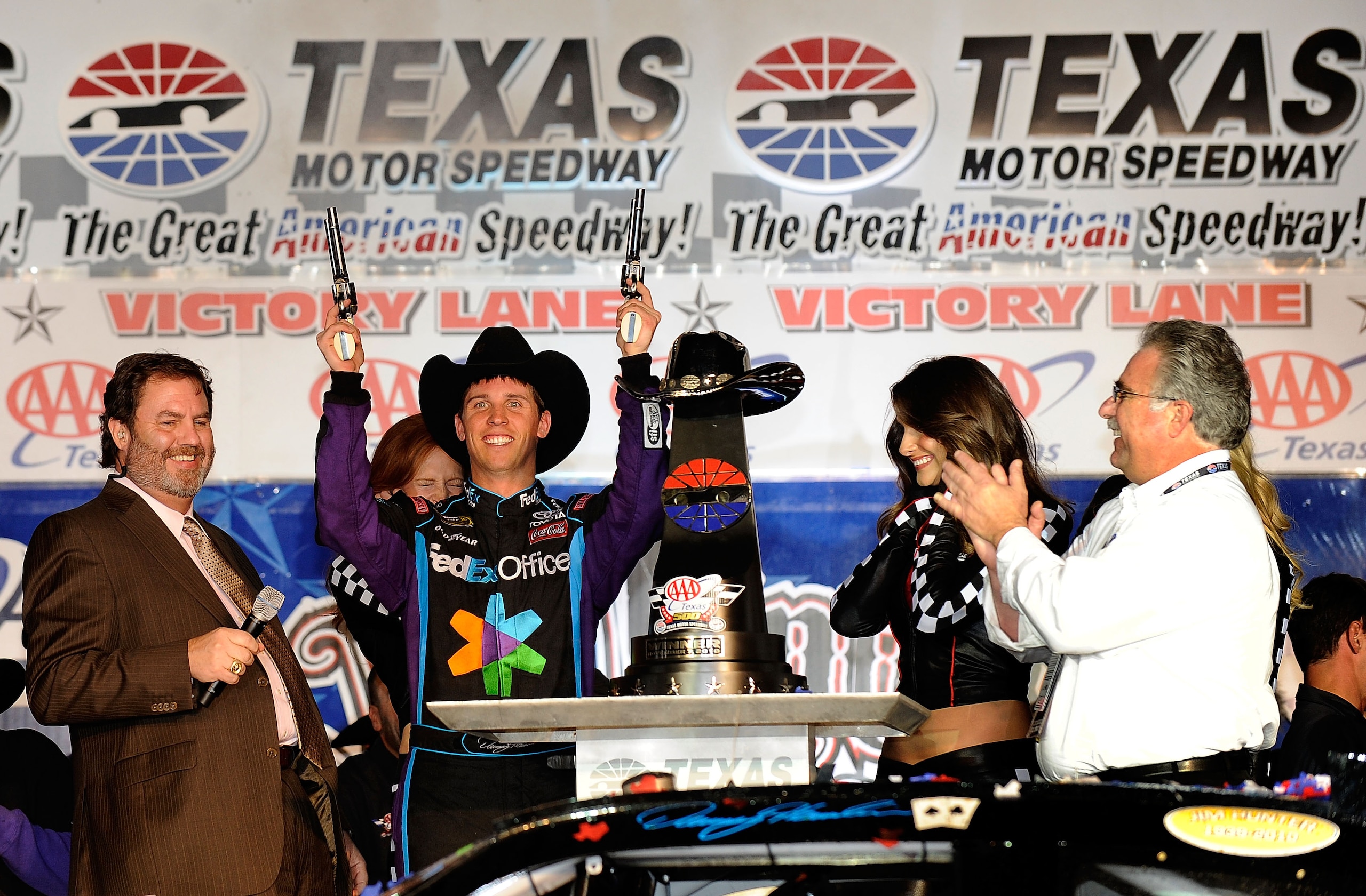 FORT WORTH, TX - NOVEMBER 07:  Texas Motor Speedway President Eddie Gossage (L) introduces Denny Hamlin (C), driver of the #11 FedEx Office Toyota, as he shoots a Turnbull Revolvers in Victory Lane after winning the NASCAR Sprint Cup Series AAA Texas 500