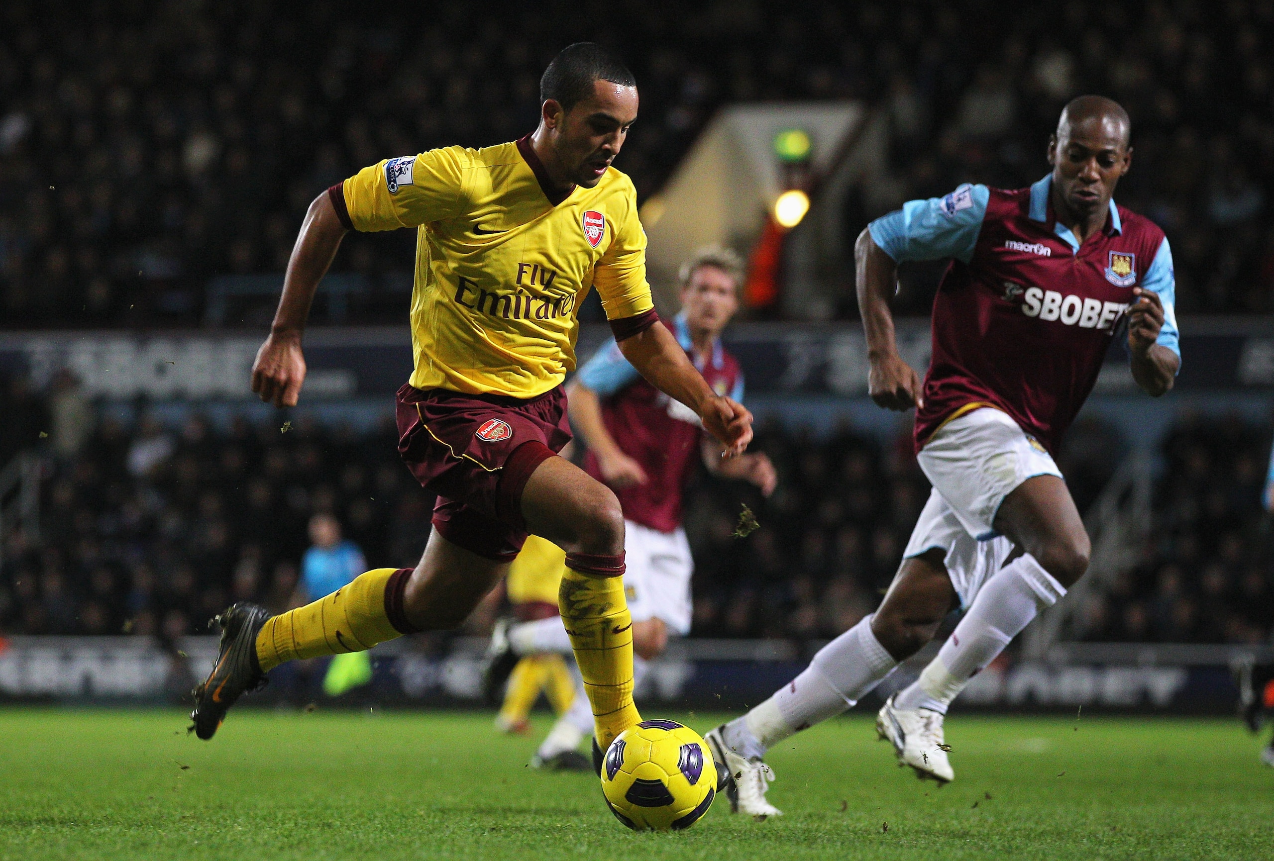 LONDON, ENGLAND - JANUARY 15:  Theo Walcott of Arsenal takes the ball past Luis Boa Morte of West Ham United during the Barclays Premier League match between West Ham United and Arsenal at the Boleyn Ground on January 15, 2011 in London, England.  (Photo
