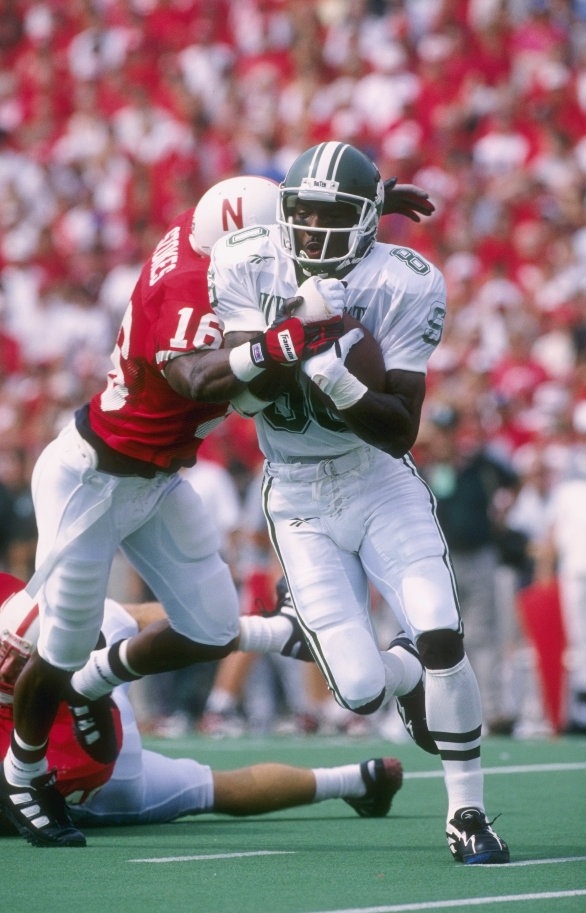 7 Sep 1996:  Wide receiver Derrick Mason of the Michigan State Spartans attempts to break free from the grasp of defensive back Eric Stokes of the Nebraska Cornhuskers during a reception in the Spartans 55-14 loss to the Cornhuskers at Memorial Stadium in