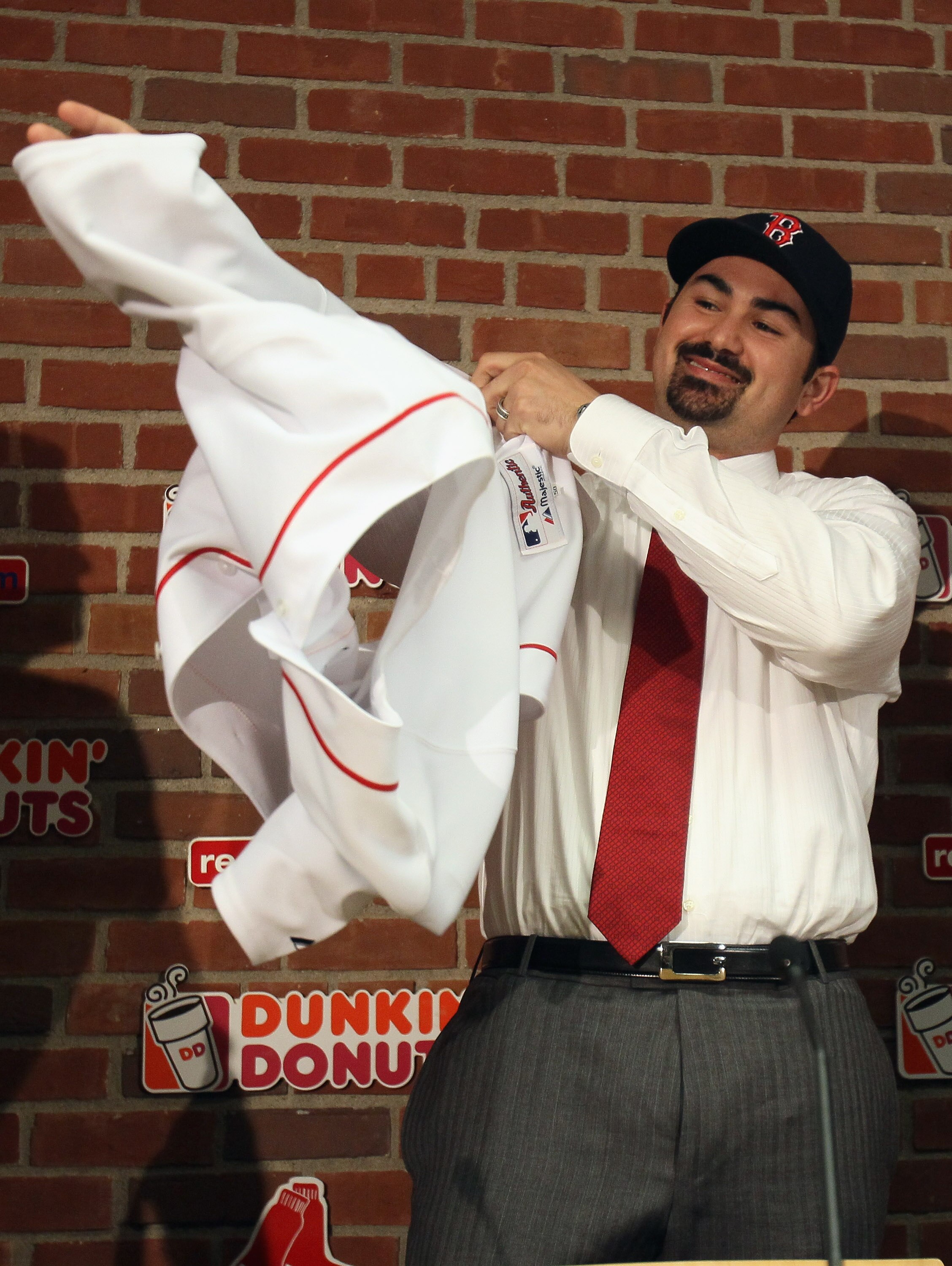 BOSTON, MA - DECEMBER 06:  Adrian Gonzalez puts on his jersey during a press conference after it was announced that he signed with the Boston Red Sox on December 6,  2010 at Fenway Park in Boston, Massachusetts.  (Photo by Elsa/Getty Images)