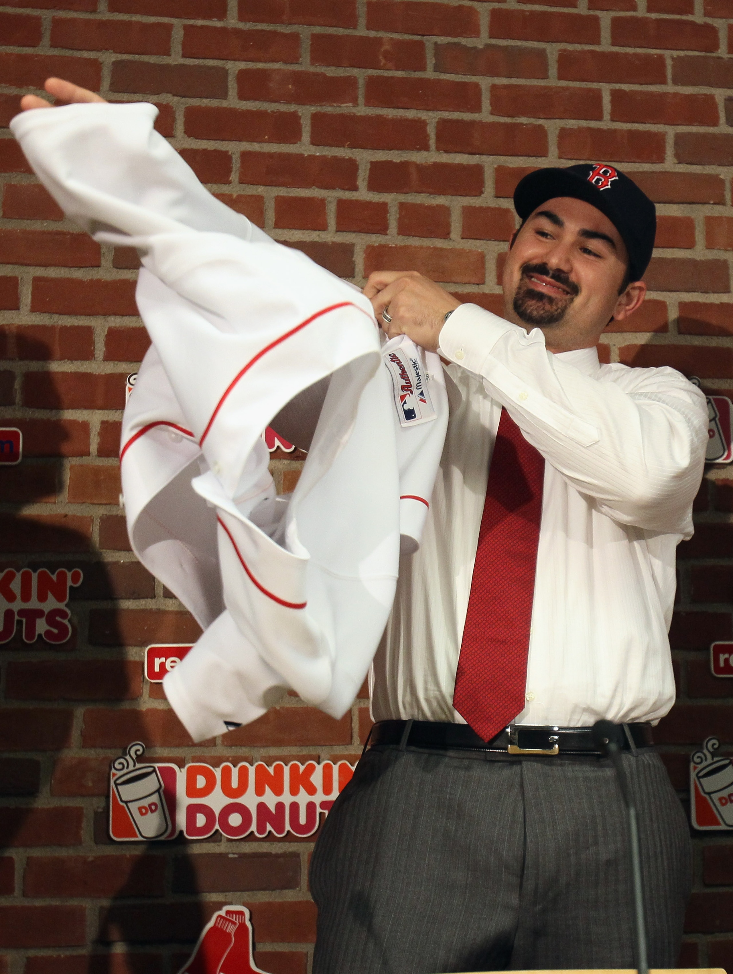 BOSTON, MA - DECEMBER 06:  Adrian Gonzalez puts on his jersey during a press conference after it was announced that he signed with the Boston Red Sox on December 6,  2010 at Fenway Park in Boston, Massachusetts.  (Photo by Elsa/Getty Images)