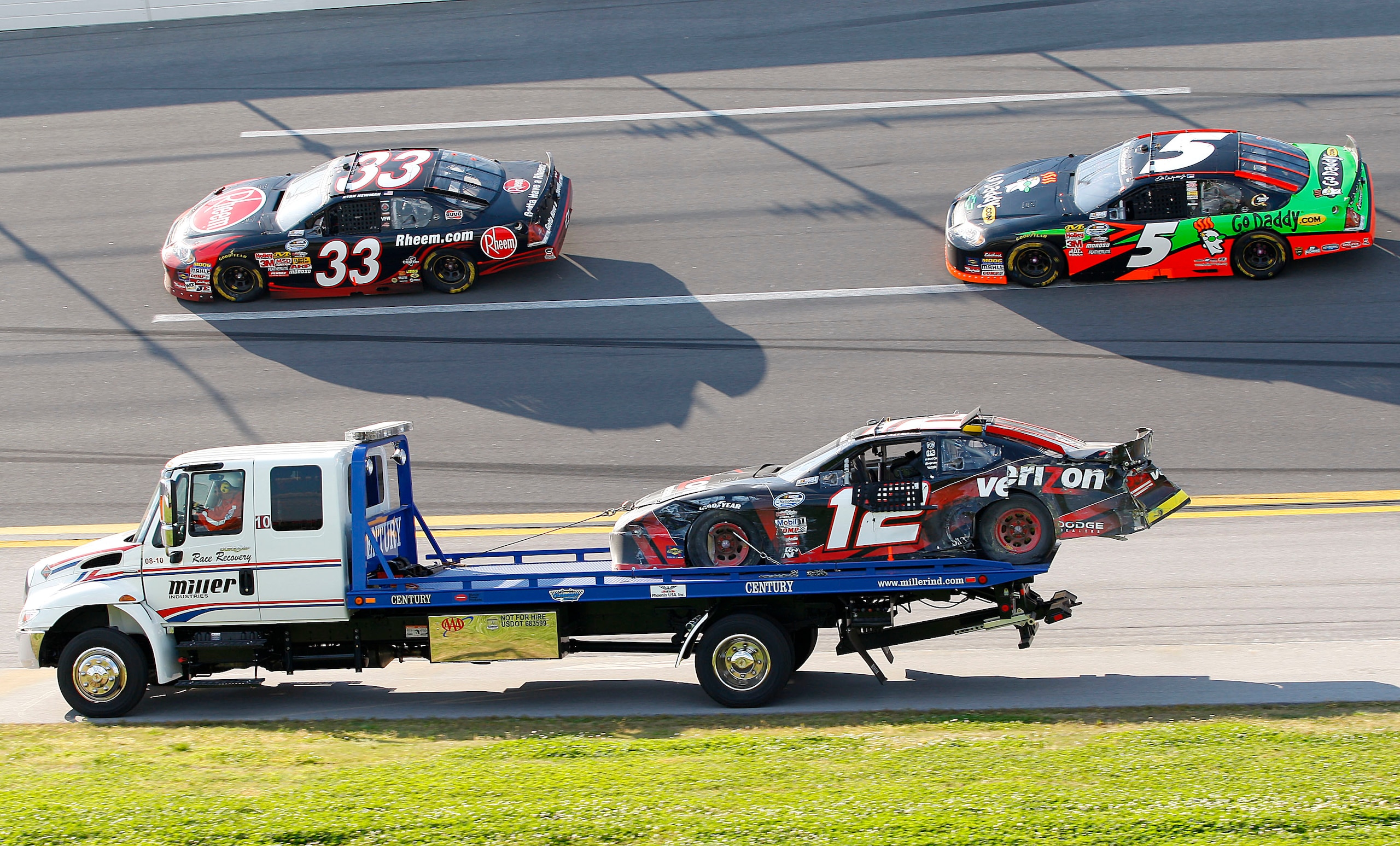 TALLADEGA, AL - APRIL 25:  The #12 Verizon Wireless Dodge driven by Justin Allgaier, is hauled off the track after a crash as Ryan Neman, driver of the #33 Rheem Chevrolet, and Dale Earnhardt Jr., driver of the #5 GoDaddy.com Chevrolet, drive past under c