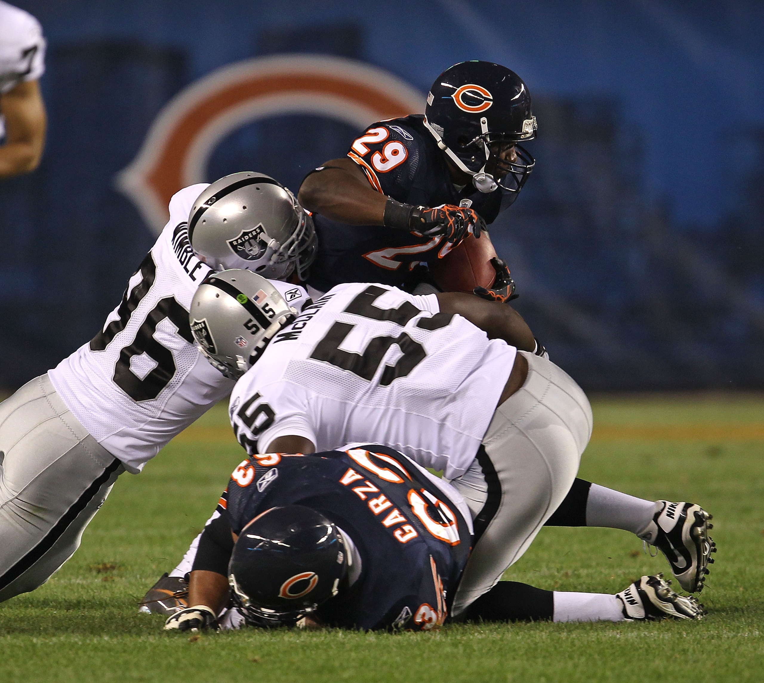 CHICAGO - AUGUST 21: Chester Taylor #29 of the Chicago Bears tries to break away from Kamerion Wimbley #96 and Rolando McClain #55 of the Oakland Raiders and past teammate Roberto Garza #63 during a preseason game at Soldier Field on August 21, 2010 in Ch