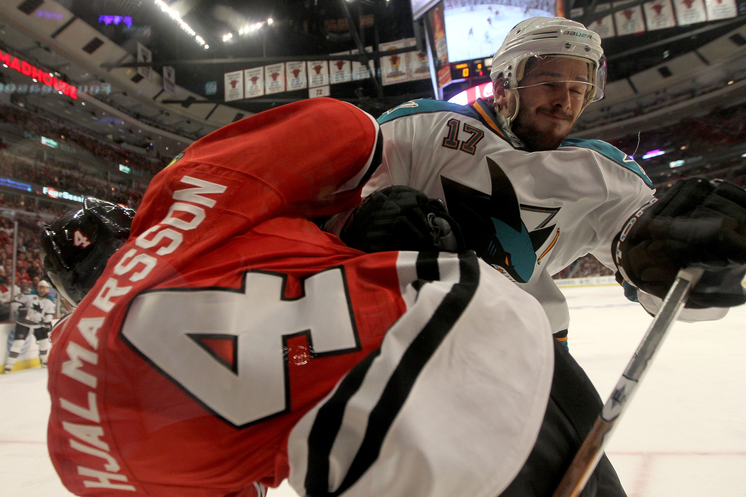 CHICAGO - MAY 21:  Torrey Mitchell #17 of the San Jose Sharks checks Niklas Hjalmarsson #4 of the Chicago Blackhawks into the boards in the first period of Game Three of the Western Conference Finals during the 2010 NHL Stanley Cup Playoffs at the United