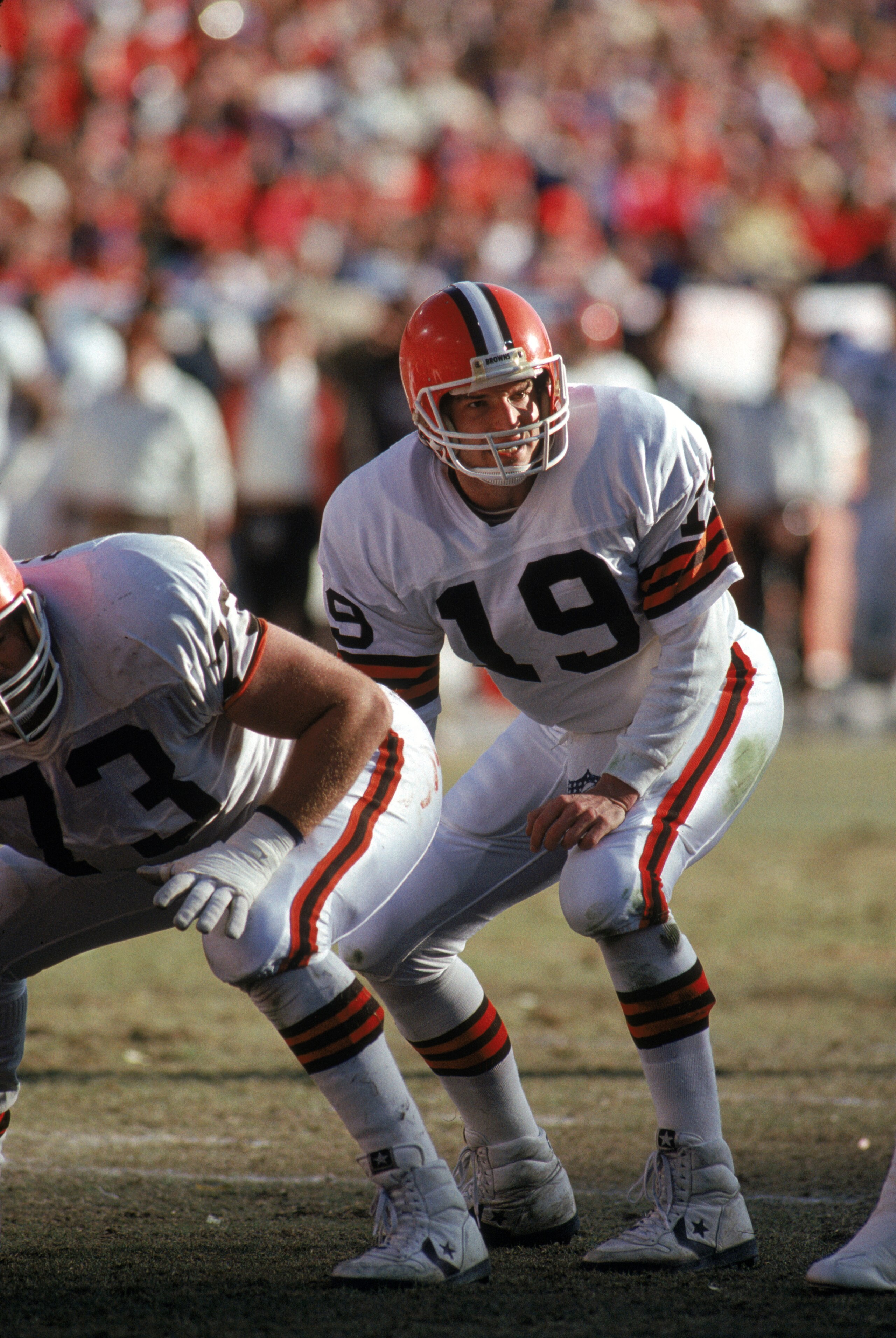 DENVER - JANUARY 17:  Quarterback Bernie Kosar #19 of the Cleveland Browns bends down for the snap during the 1987 AFC Championship game against the Denver Broncos at Mile High Stadium on January 17, 1988 in Denver, Colorado.  The Broncos won 38-33.  (Pho