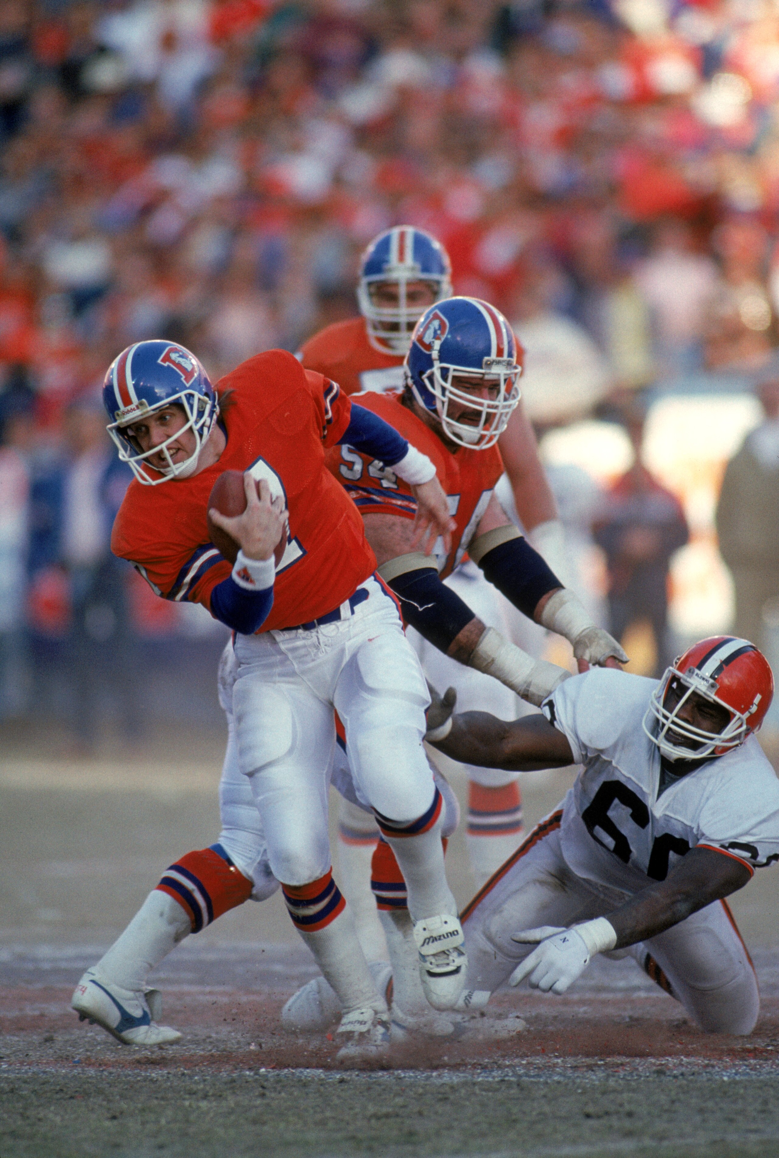 DENVER - JANUARY 17:  Quarterback John Elway #7 of the Denver Broncos breaks a tackle during the 1987 AFC Championship game against the Cleveland Browns at Mile High Stadium on January 17, 1988 in Denver, Colorado.  The Broncos won 38-33.  (Photo by Georg