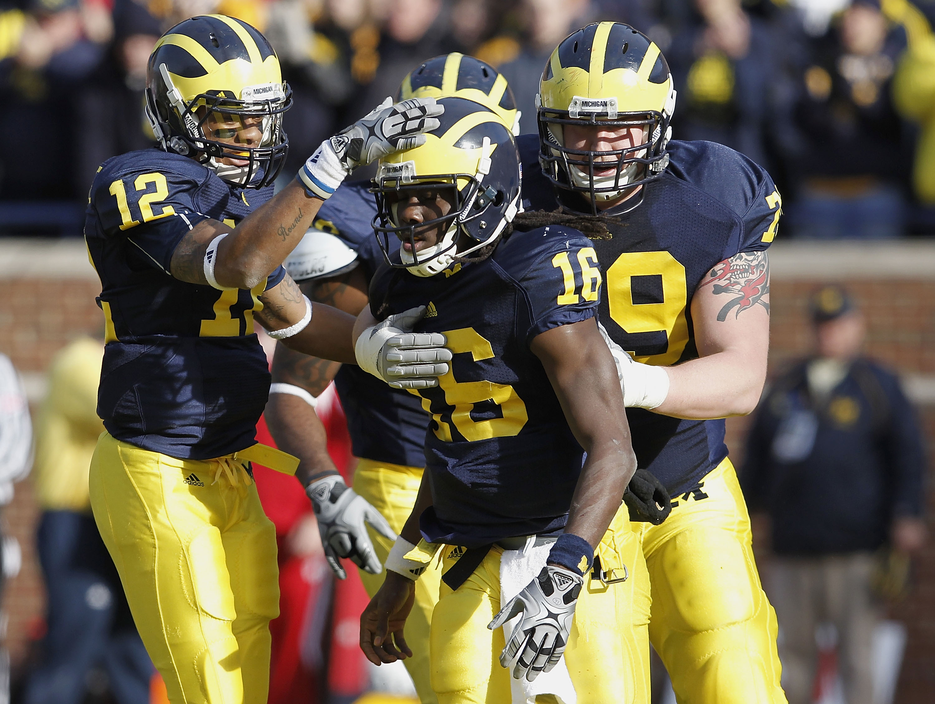 ANN ARBOR, MI - NOVEMBER 20:  Denard Robinson #16 of the Michigan Wolverines is congratulated by Roy Roundtree #12 and Perry Dorrenstein #79 after a third quarter touchdown against the Wisconsin Badgers at Michigan Stadium on November 20, 2010 in Ann Arbo