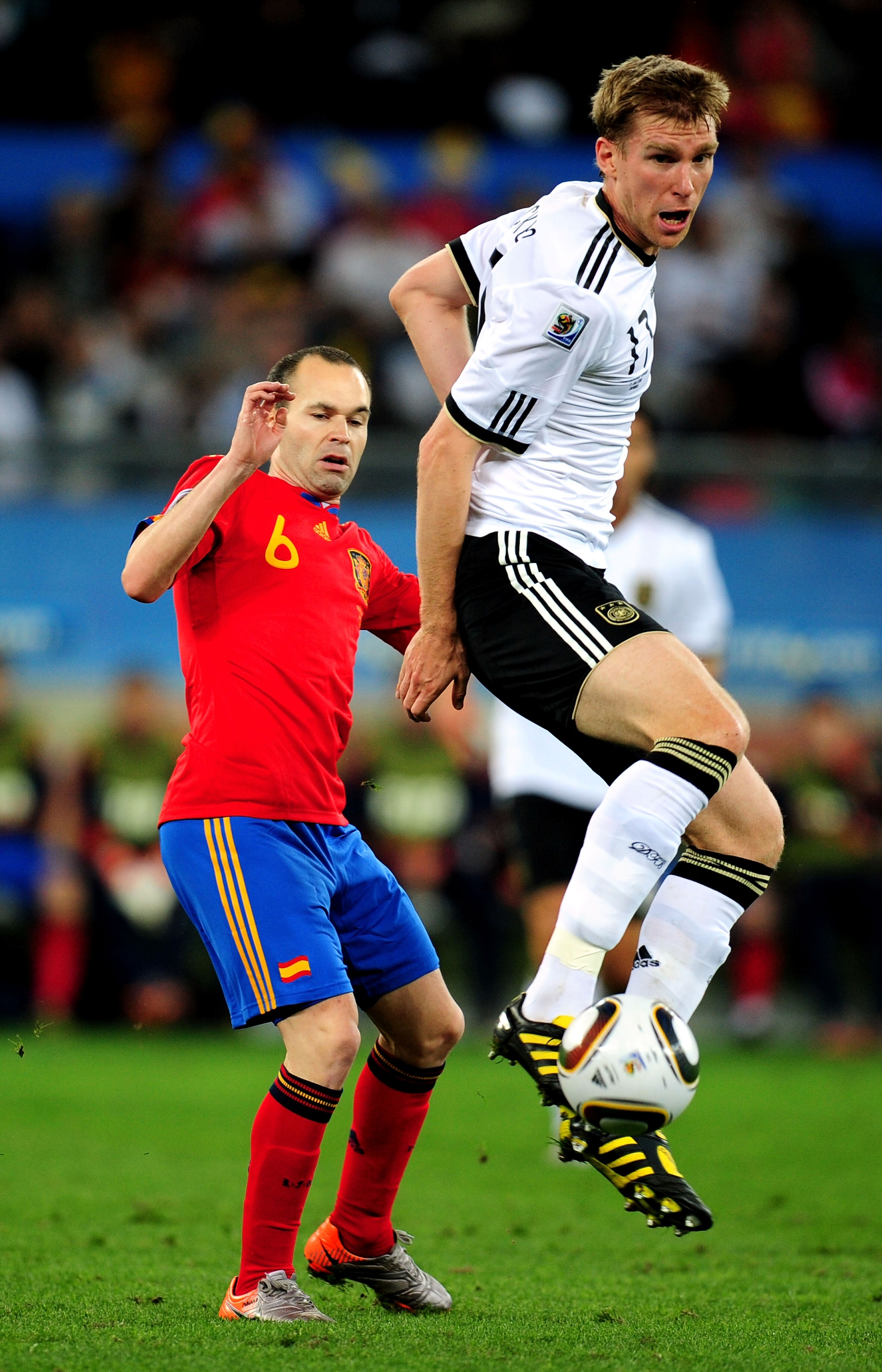 DURBAN, SOUTH AFRICA - JULY 07:  Per Mertesacker of Germany controls the ball ahead of Andres Iniesta of Spain during the 2010 FIFA World Cup South Africa Semi Final match between Germany and Spain at Durban Stadium on July 7, 2010 in Durban, South Africa