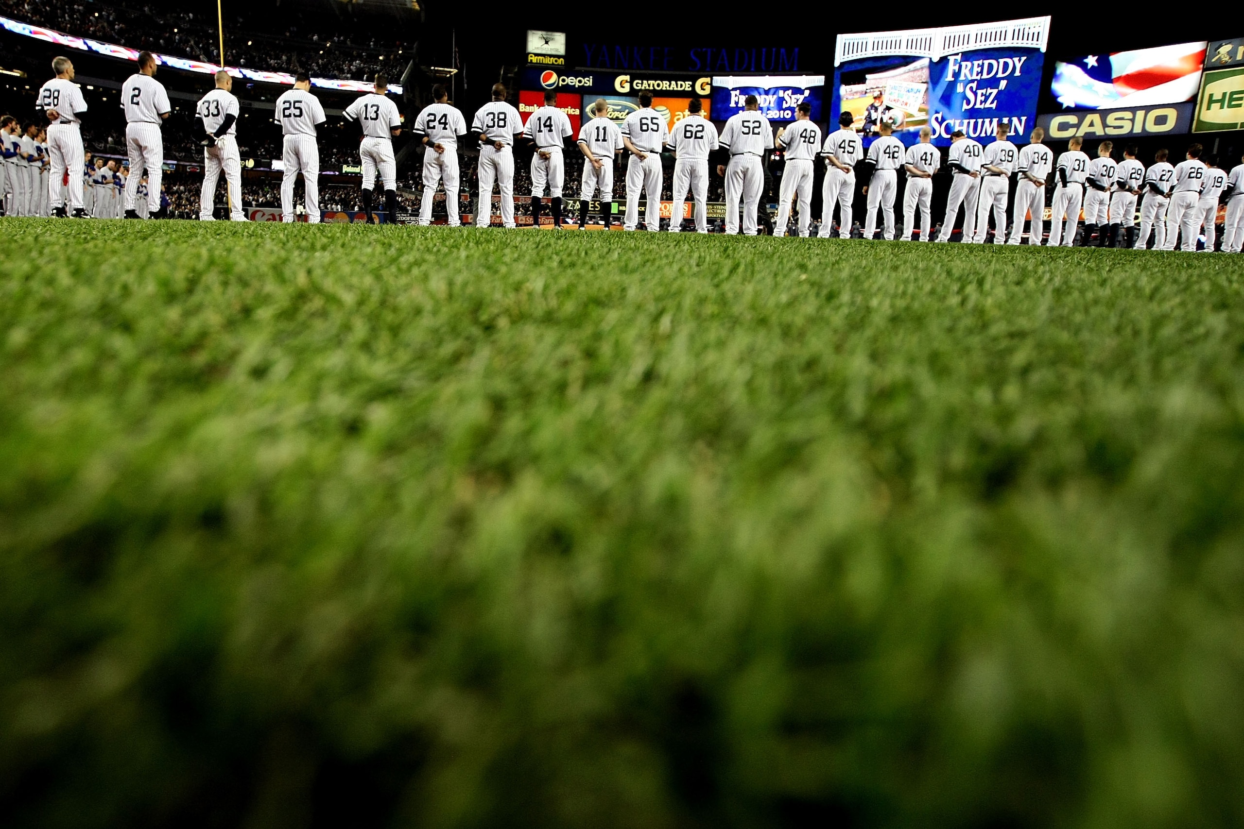 NEW YORK - OCTOBER 18:  Members of the New York Yankees stand in silence as they remember deceased Yankee fan Freddy 'Freddy Sez' Schuman before playing against the Texas Rangers in Game Three of the ALCS during the 2010 MLB Playoffs at Yankee Stadium on