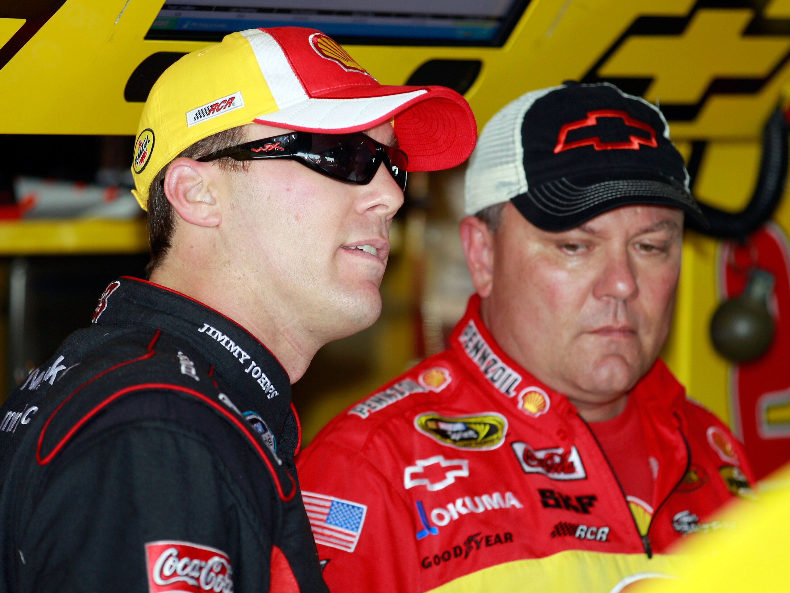 HOMESTEAD, FL - NOVEMBER 20:  Kevin Harvick (L), driver of the #29 Shell/Pennzoil Chevrolet, talks with crew chief Gil Martin (R) in the garage with a crew member during practice for the NASCAR Sprint Cup Series Ford 400 at Homestead-Miami Speedway on Nov