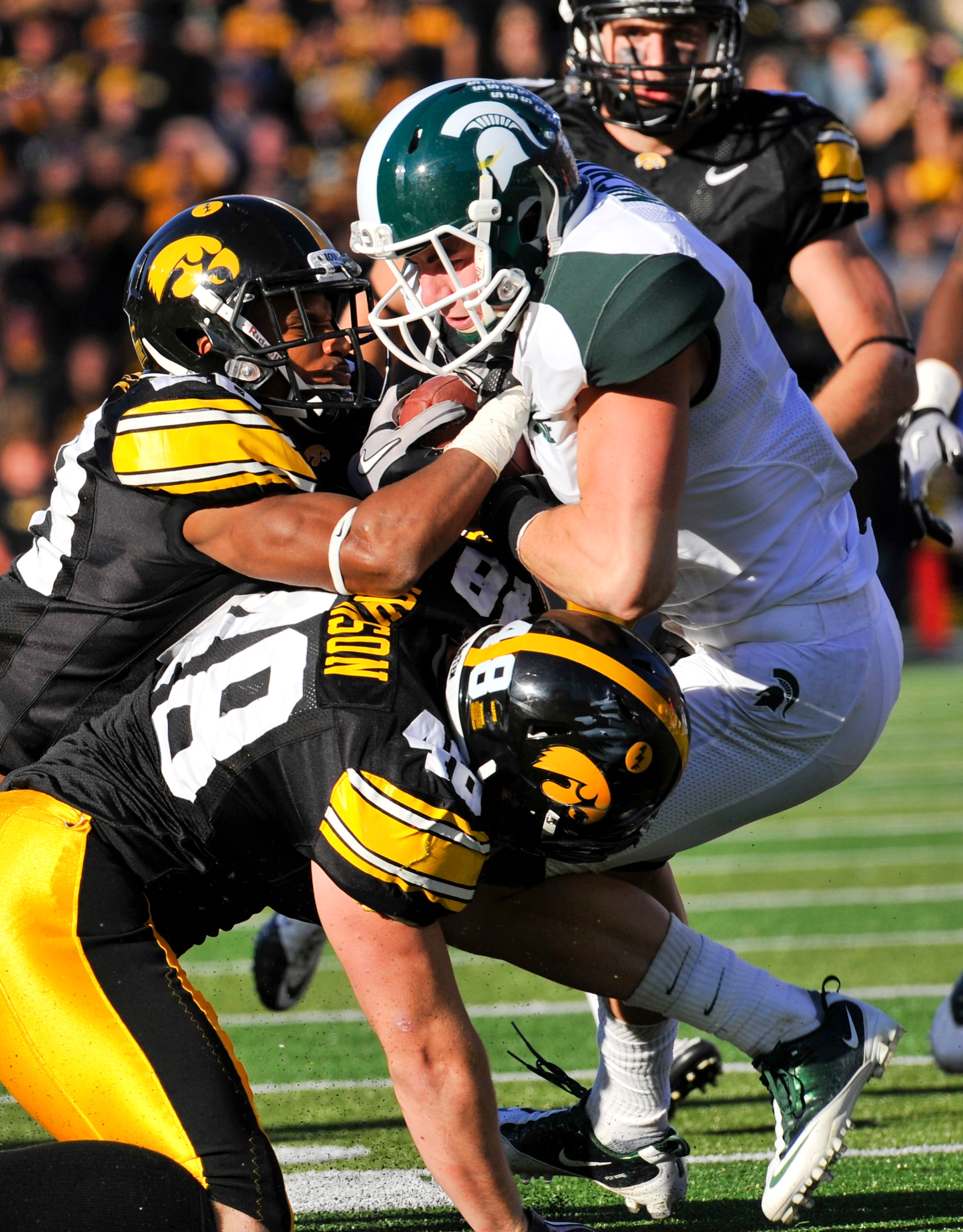 IOWA CITY, IA - OCTOBER 30: Line backer Troy Johnson #48 and defensive back Shaun Prater #28 of the University of Iowa Hawkeyes tackle wide receiver Keith Nichol #7 of the Michigan State Spartans during the first half of play at Kinnick Stadium on October IOWA CITY, IA - OCTOBER 30: Line backer Troy Johnson #48 and defensive back Shaun Prater #28 of the University of Iowa Hawkeyes tackle wide receiver Keith Nichol #7 of the Michigan State Spartans during the first half of play at Kinnick Stadium on October