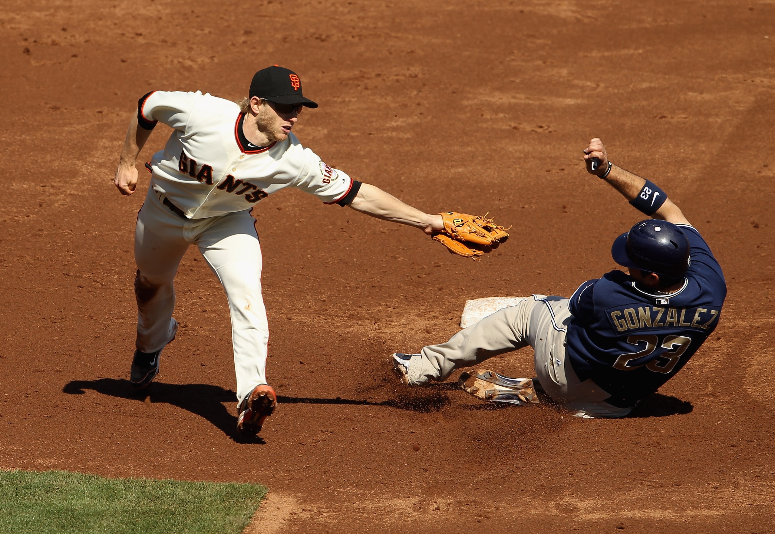 SAN FRANCISCO - OCTOBER 02:  Adrian Gonzalez #23 of the San Diego Padres slides to avoid the tag of Mike Fontenot #14 of the San Francisco Giants that was wide due to a throwing error by Pablo Sandoval at AT&T Park on October 2, 2010 in San Francisco, Cal