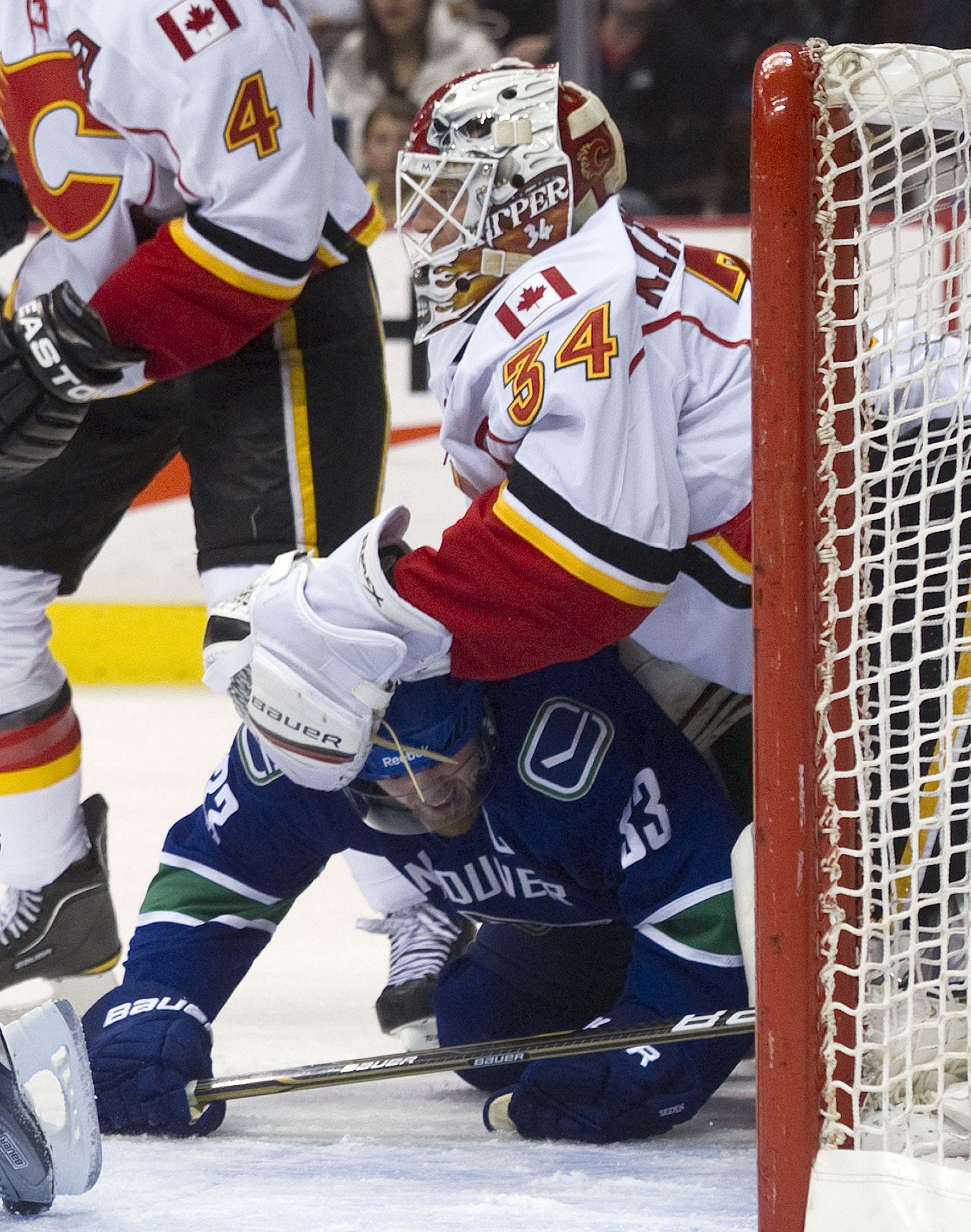 VANCOUVER, CANADA - JANUARY 5: Henrik Sedin #33 of the Vancouver Canucks gets tangled up with goalie Miikka Kiprusoff #34 of the Calgary Flames during the second period in NHL action on January 05, 2011 at Rogers Arena in Vancouver, BC, Canada.  (Photo by