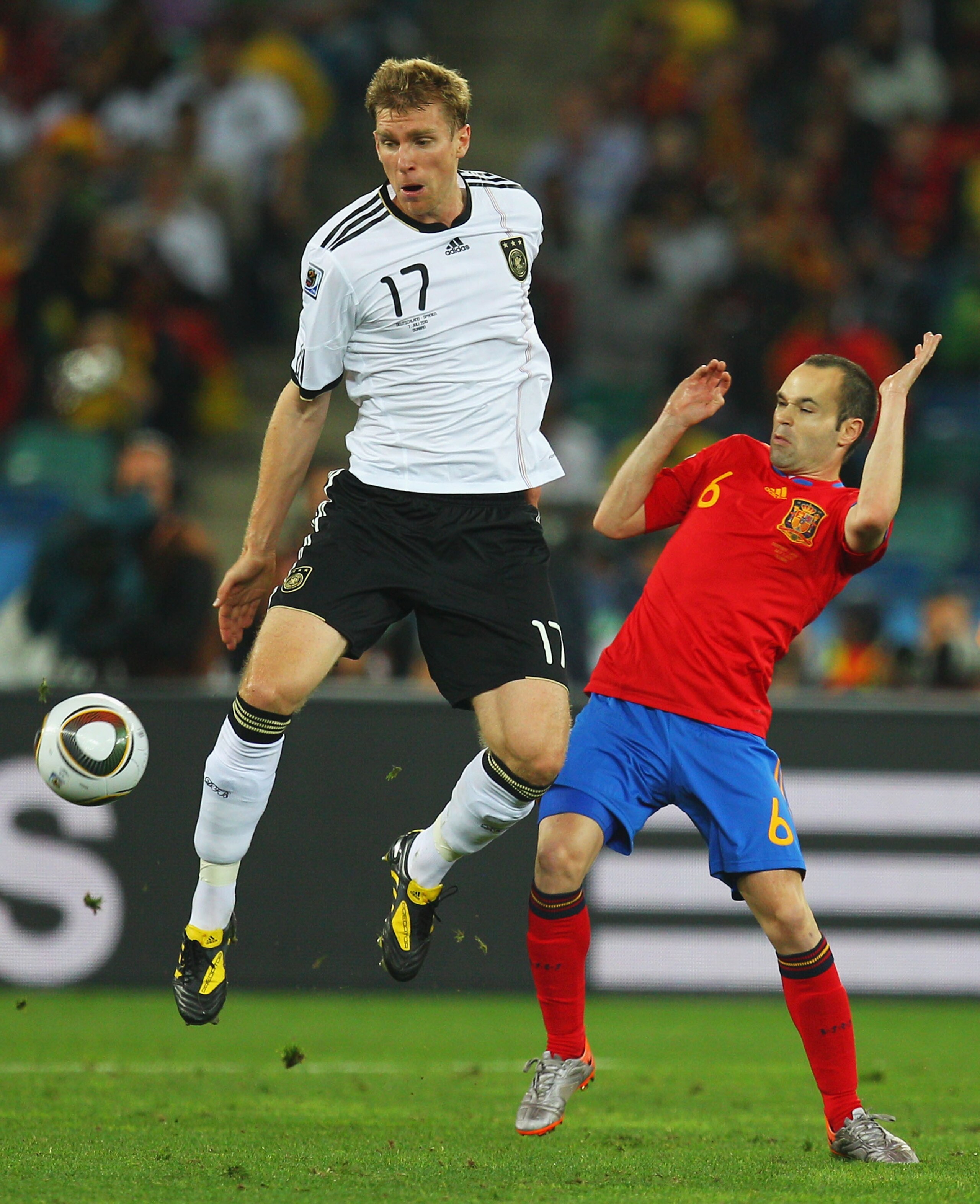 DURBAN, SOUTH AFRICA - JULY 07: Per Mertesacker of Germany and Andres Iniesta of Spain challenge for the ball during the 2010 FIFA World Cup South Africa Semi Final match between Germany and Spain at Durban Stadium on July 7, 2010 in Durban, South Africa.