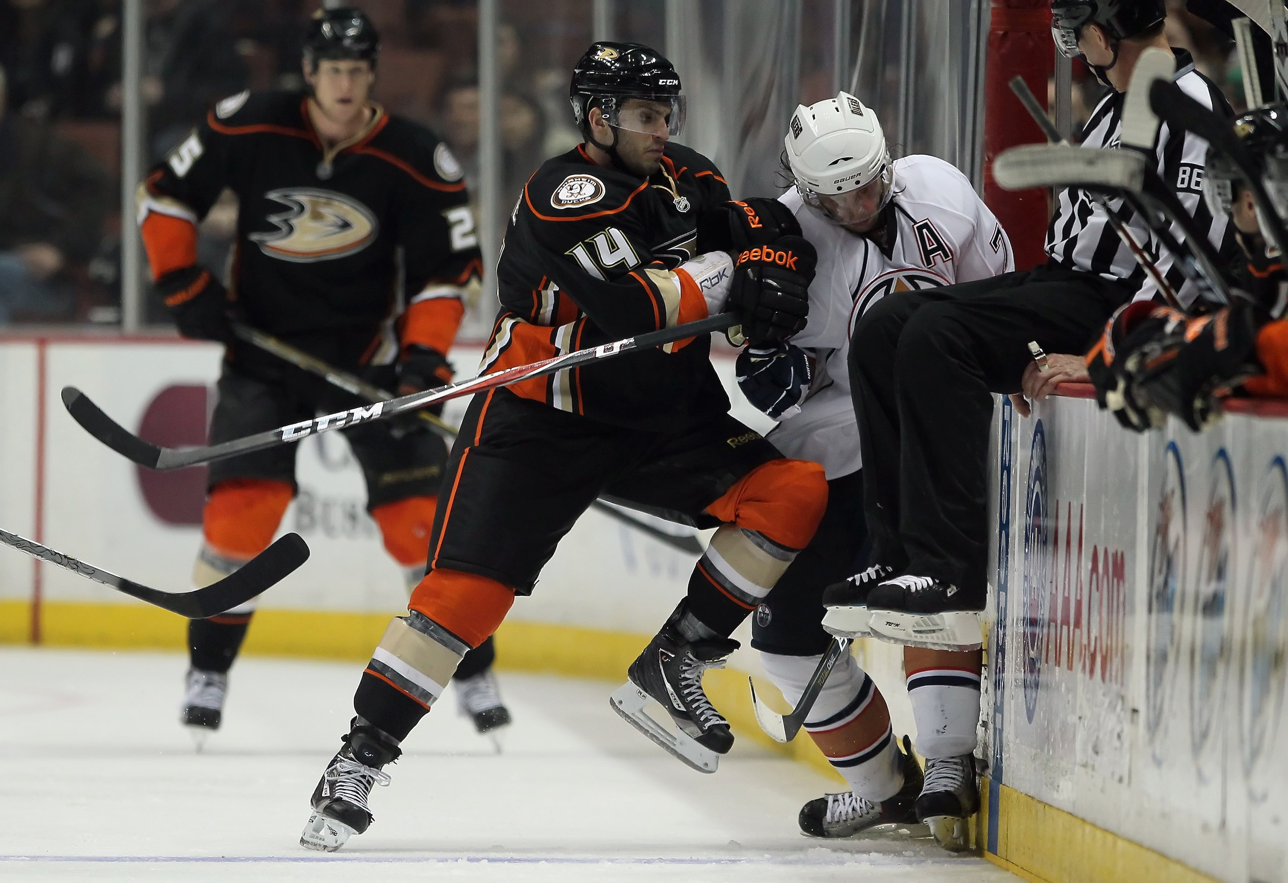 ANAHEIM, CA - JANUARY 16:  Maxim Lapierre #14 of the Anaheim Ducks hits Tom Gilbert #77 of the Edmonton Oilers into the boards in the third period at the Honda Center on January 16, 2011 in Anaheim, California. The Ducks defeated the Oilers 3-2.  (Photo b
