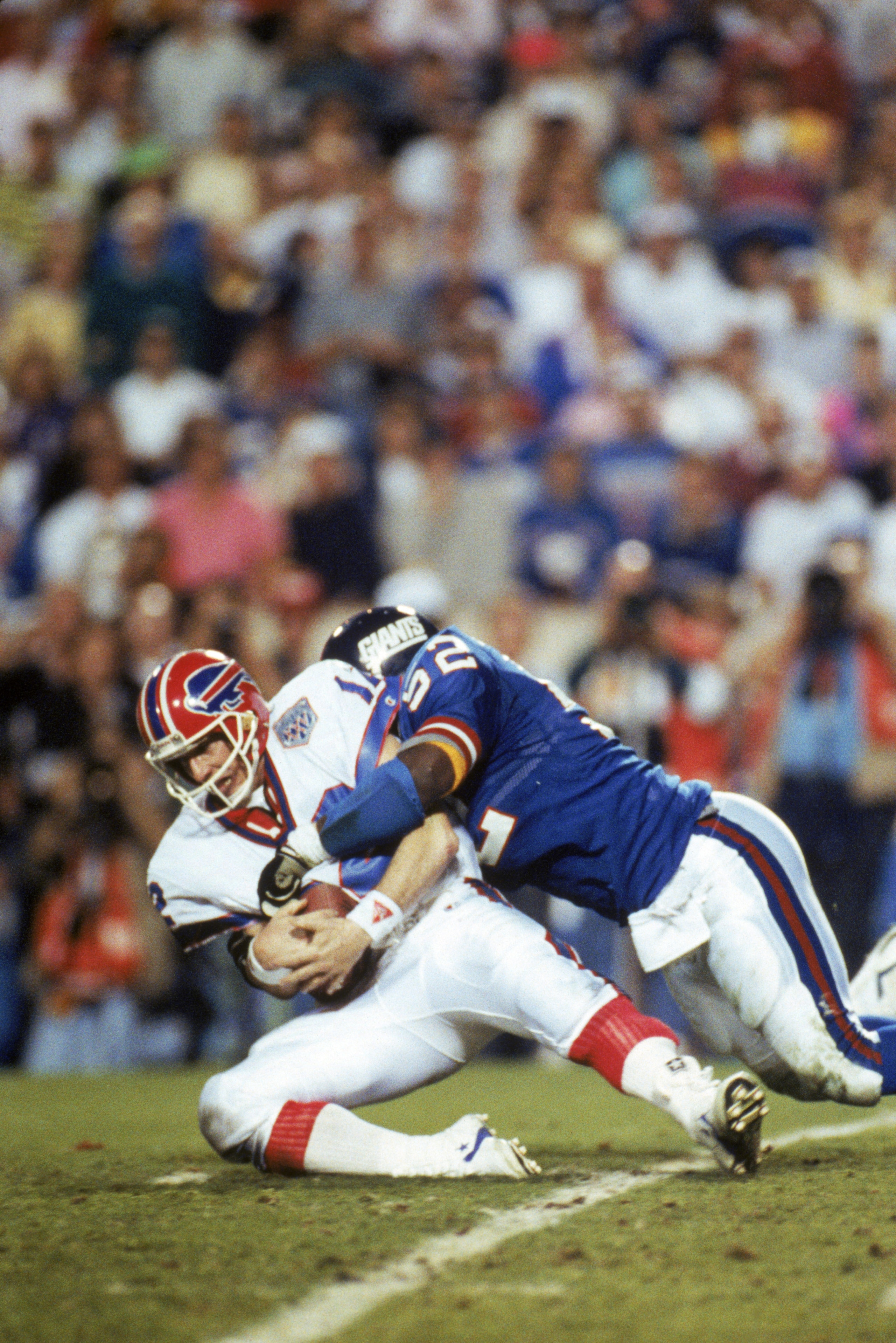 TAMPA, FL - JANUARY 27:  Linebacker Pepper Johnson #52 of the New York Giants tackles quarterback Jim Kelly #12 of the Buffalo Bills after a one yard gain in the fourth quarter of Super Bowl XXV at Tampa Stadium on January 27, 1991 in Tampa, Florida.  The