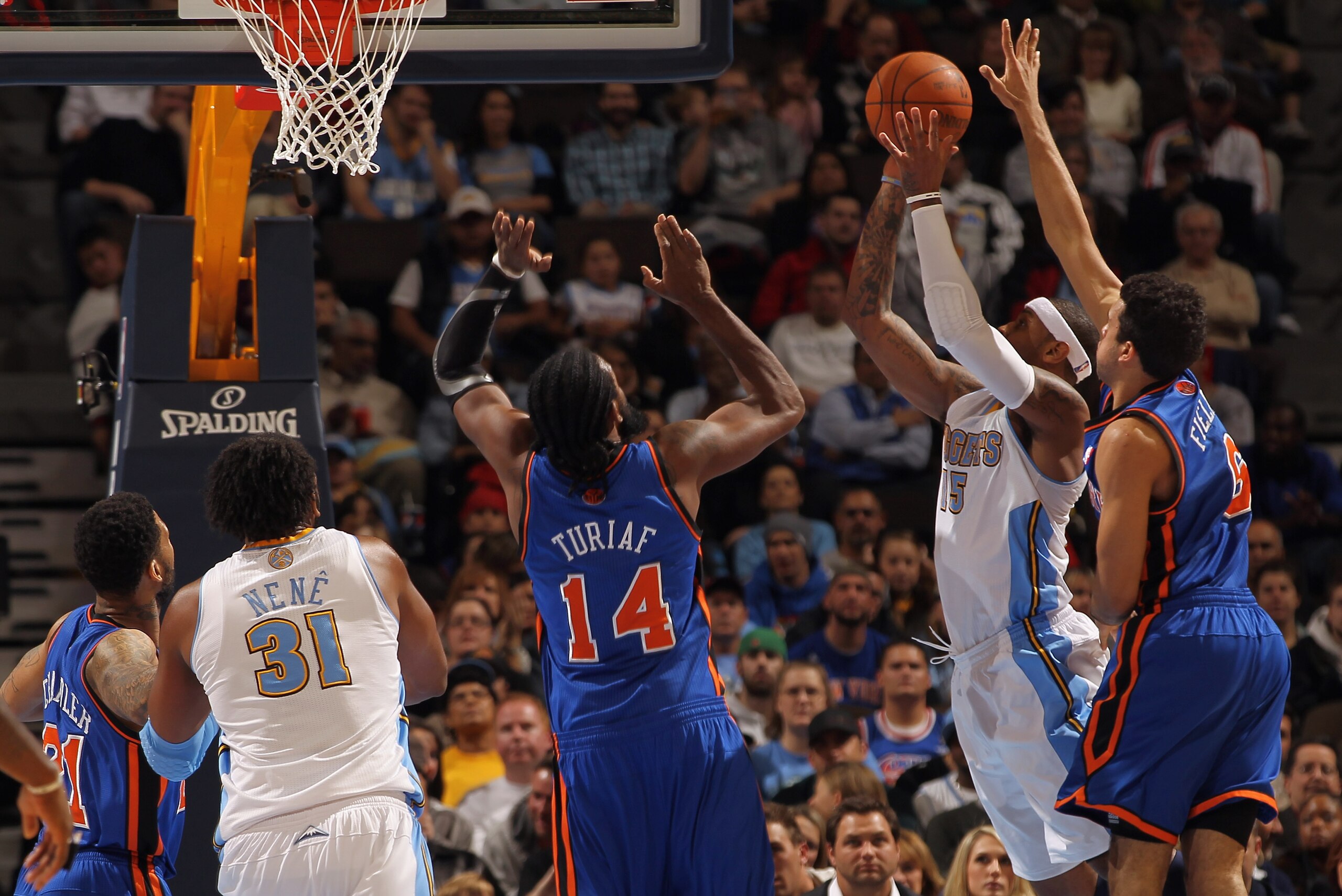 DENVER - NOVEMBER 16:  Carmelo Anthony #15 of the Denver Nuggets takes a shot between Landry Fields #6 and Ronny Turiaf #14 of the New York Knicks at the Pepsi Center on November 16, 2010 in Denver, Colorado. The Nuggets defeated the Knicks 120-118. NOTE